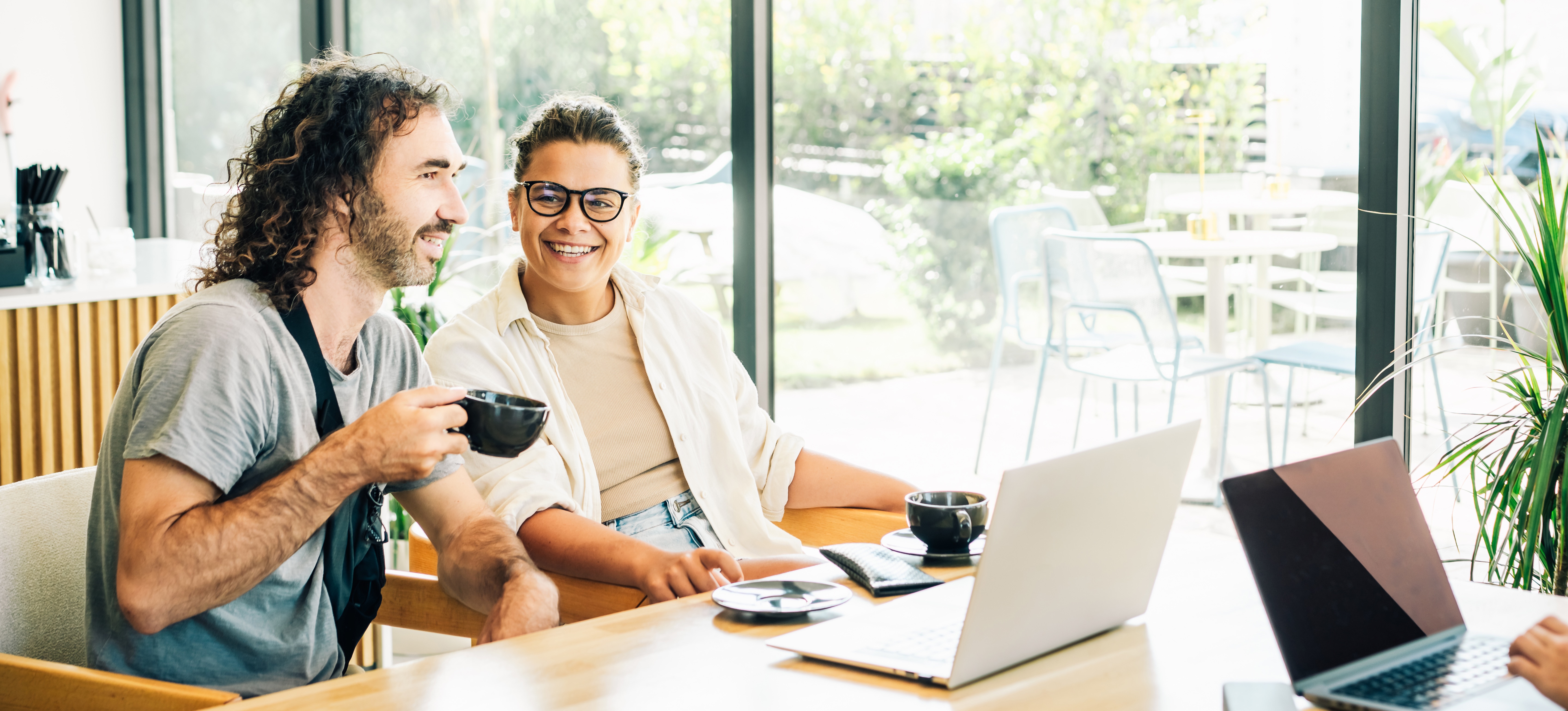 [Feature Image] Two cybersecurity professionals discuss the ISC2 certifications they are preparing for as they study in a brightly lit room and drink coffee.
