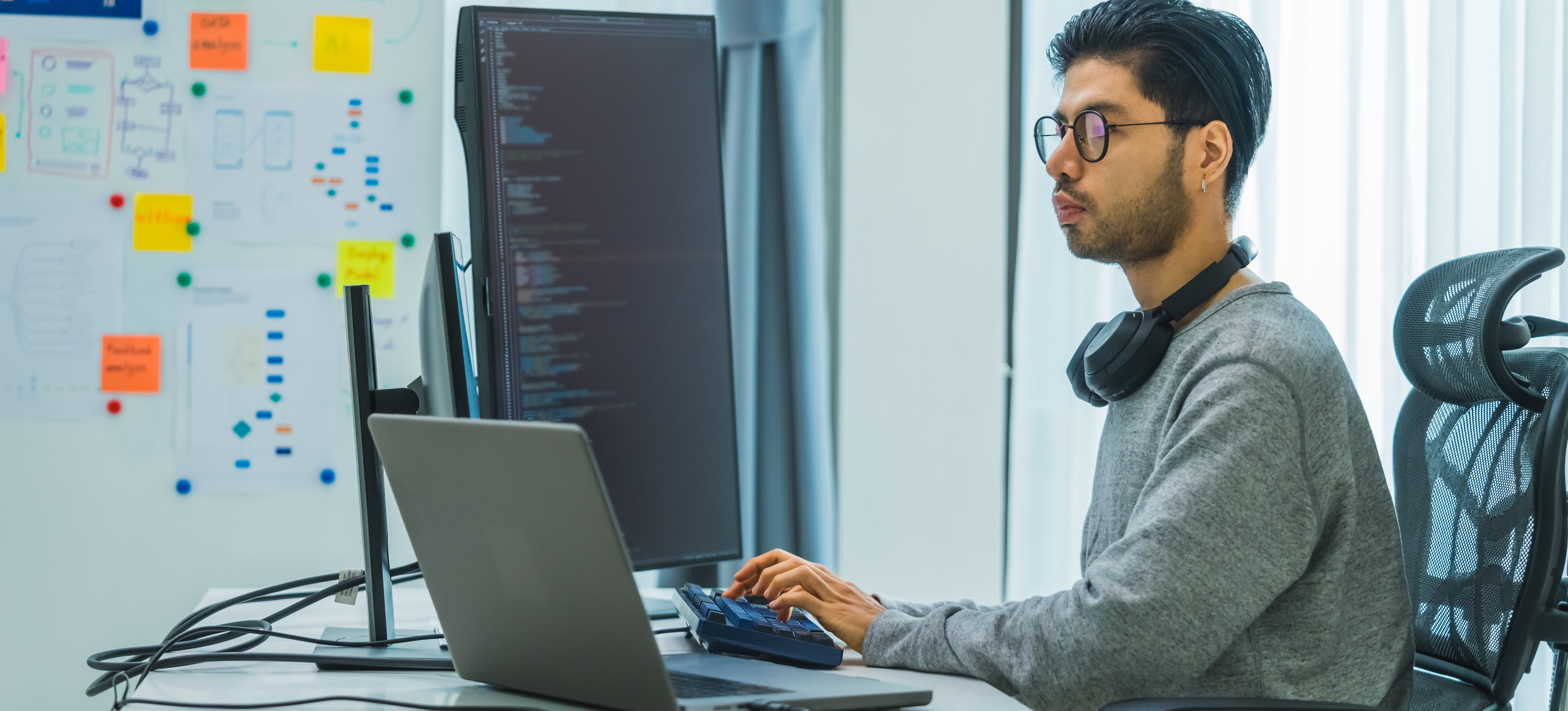 [Featured Image] A mobile app developer sits at a workstation, helping to create a new app.