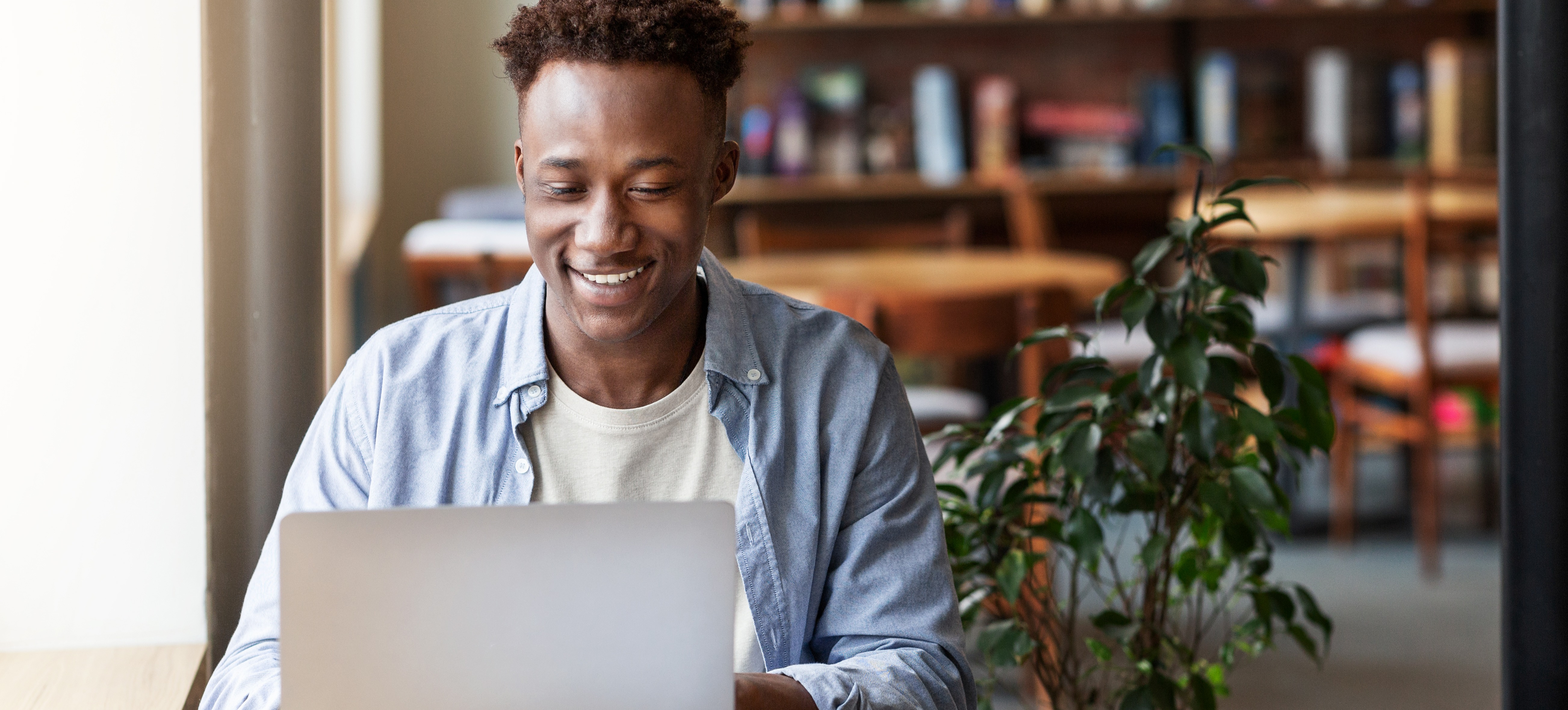 [Featured image] A person sits at a table with their laptop and prepares to earn the SC-900 certification.
