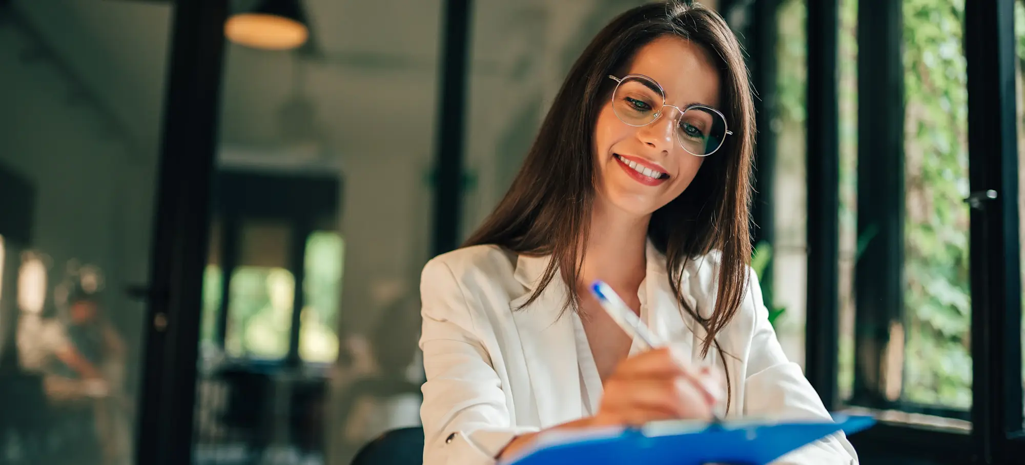 [Featured Image] Applicant writes a cover letter on a blue clipboard.