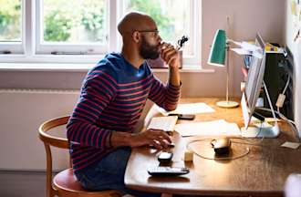 [Featured image] A full-stack developer wearing a blue and red-striped sweater sits at a wooden desk in a home office working on a desktop computer.