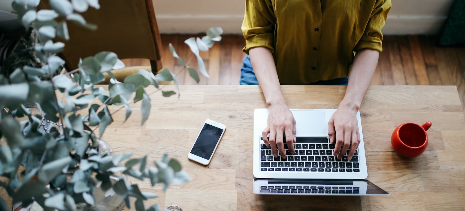 [Featured image] An SEO works on earning their Google Analytics Certification on a laptop computer. They have their phone and a red mug sitting on the table in front of them.