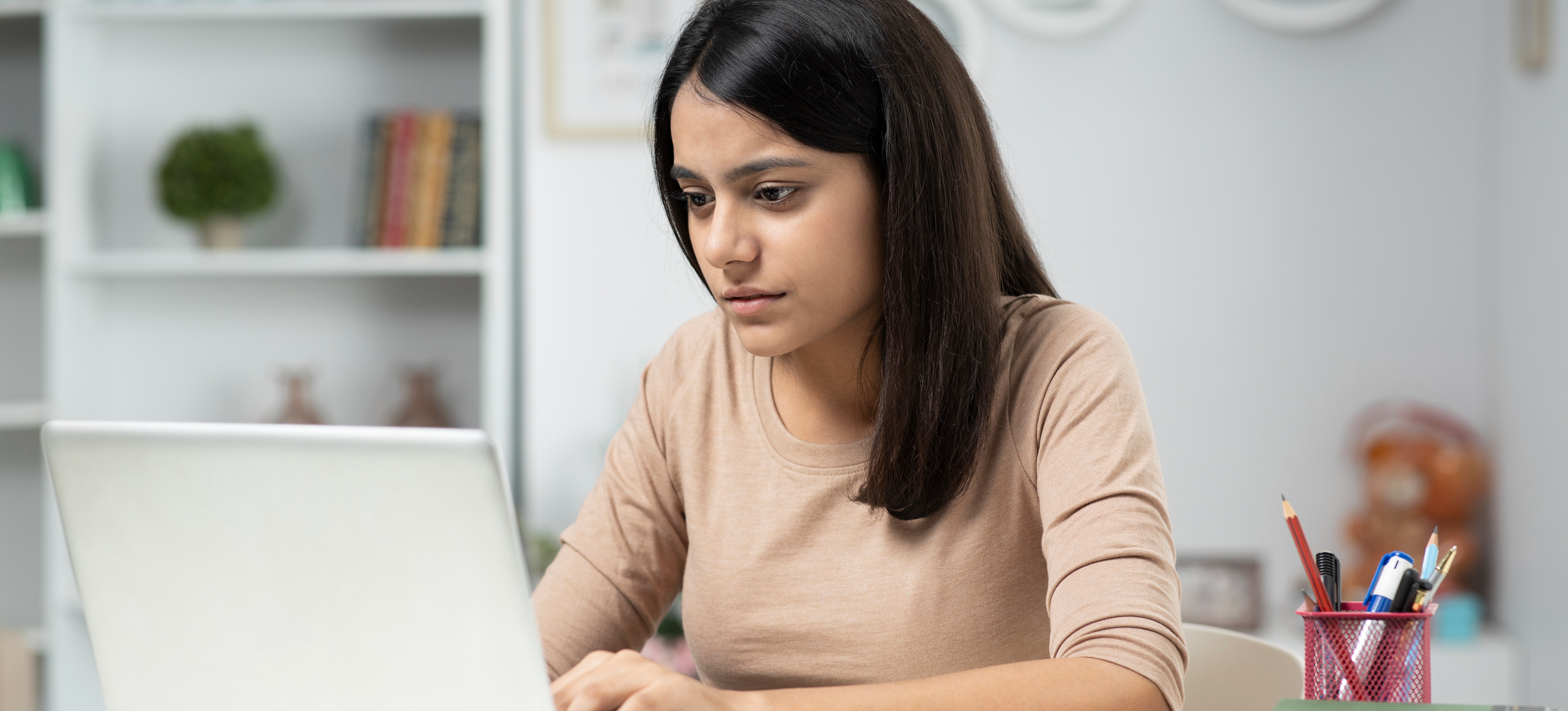 [Featured Image]: A woman works on a laptop as she explores AWS certification to advance her career.
