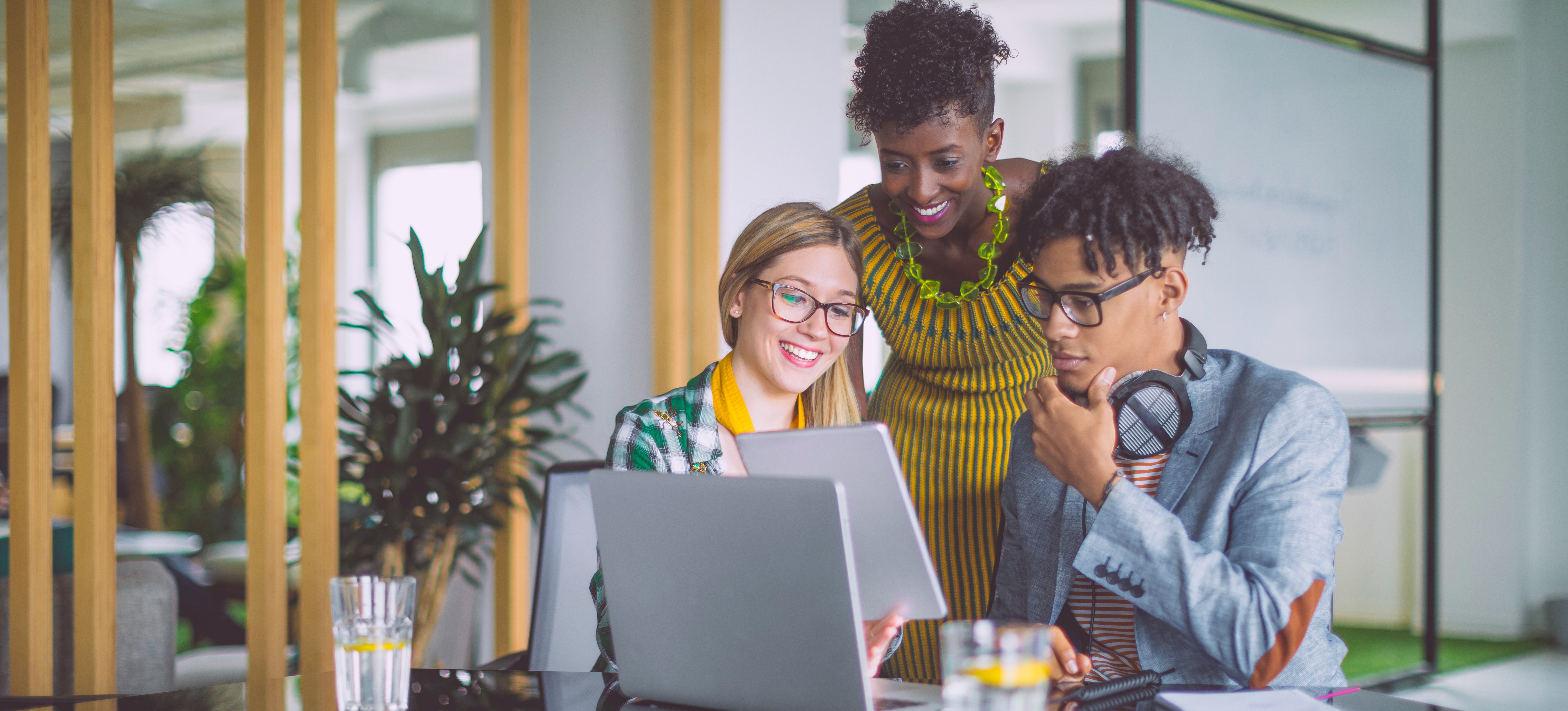 [Featured Image] Three people in an office conference room looking at a tablet and researching the best AI companies to work for.
