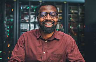 [Featured image] A male manual tester, wearing a brown shirt, glasses is sitting in front of his desktop.