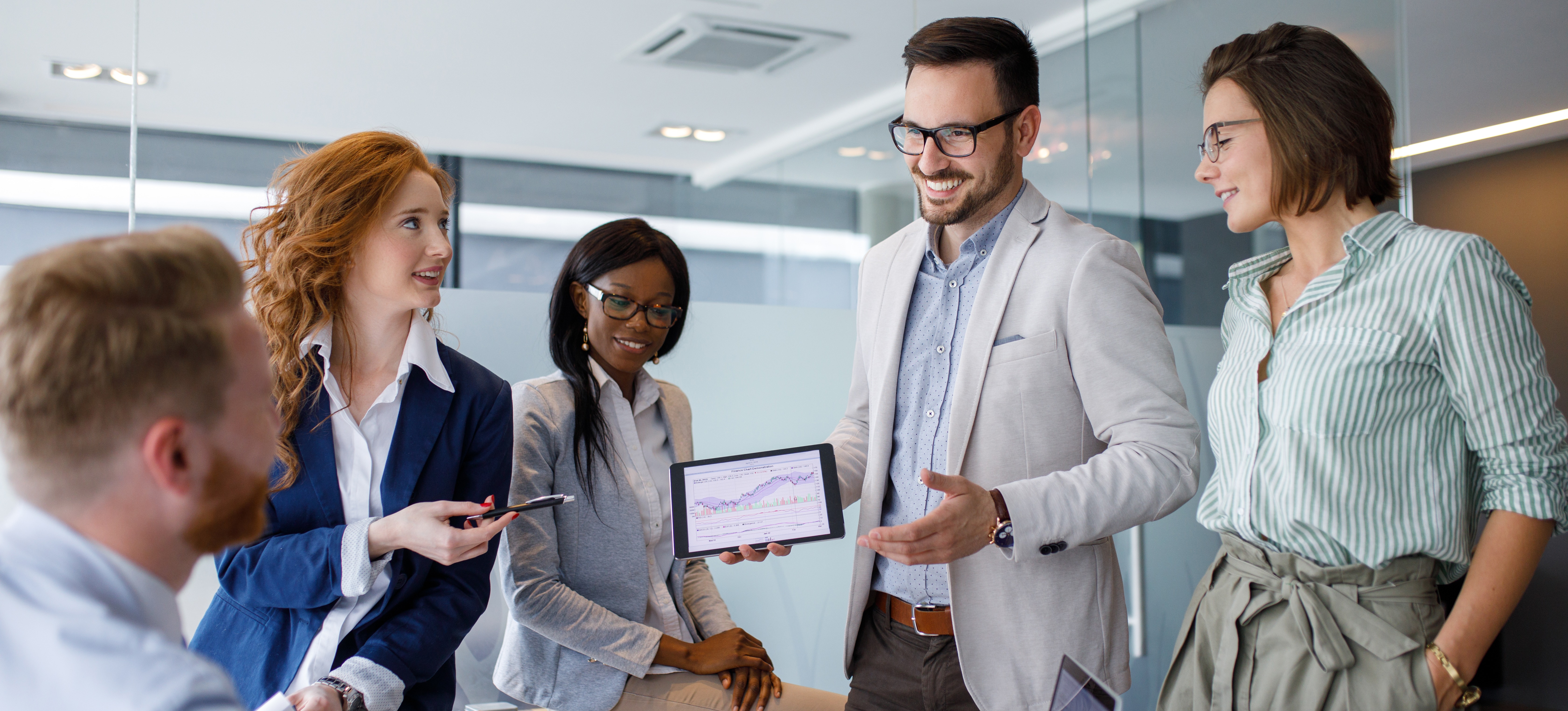[Featured Image] A group of salespeople discuss results showing a low churn rate for their company.
