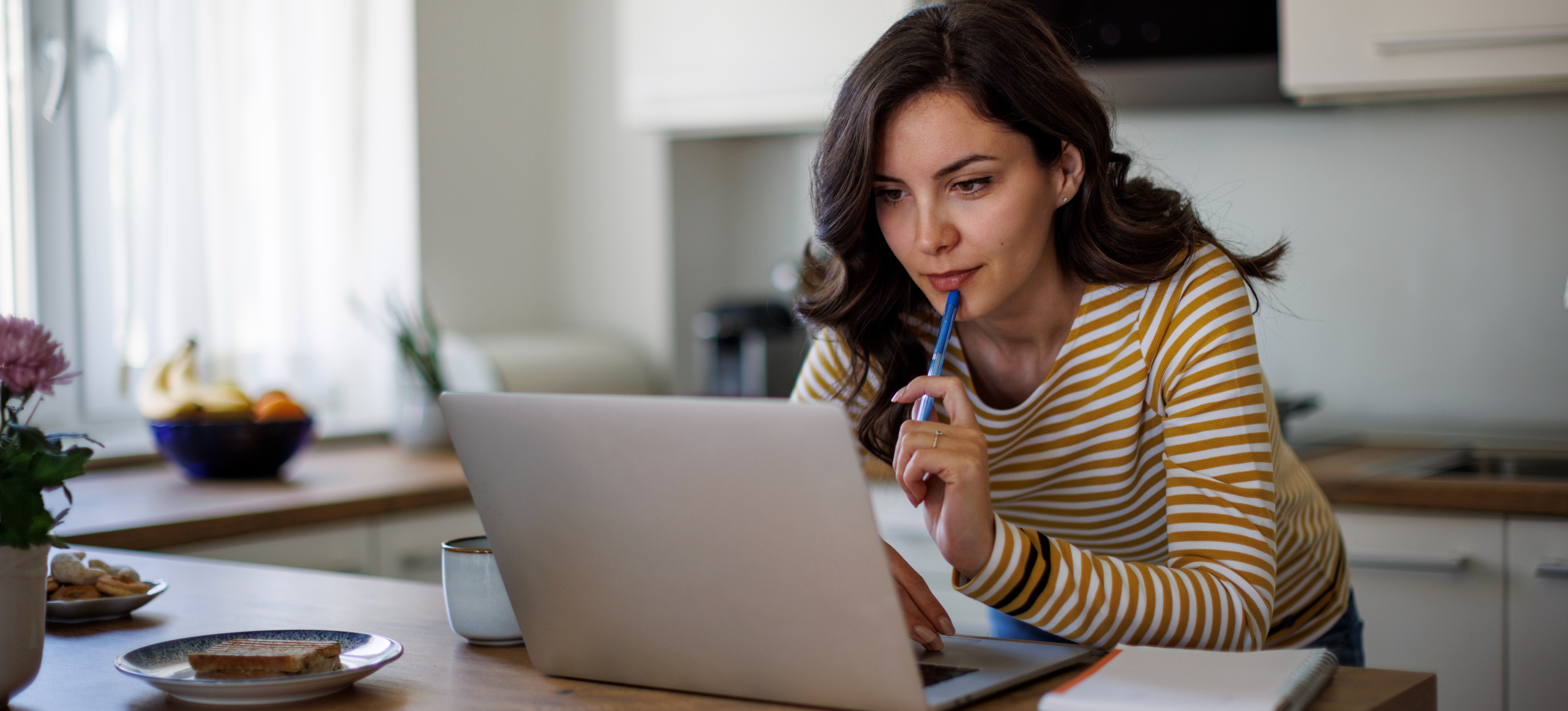 [Featured Image] A person works on their career change resume at a laptop in their kitchen. 