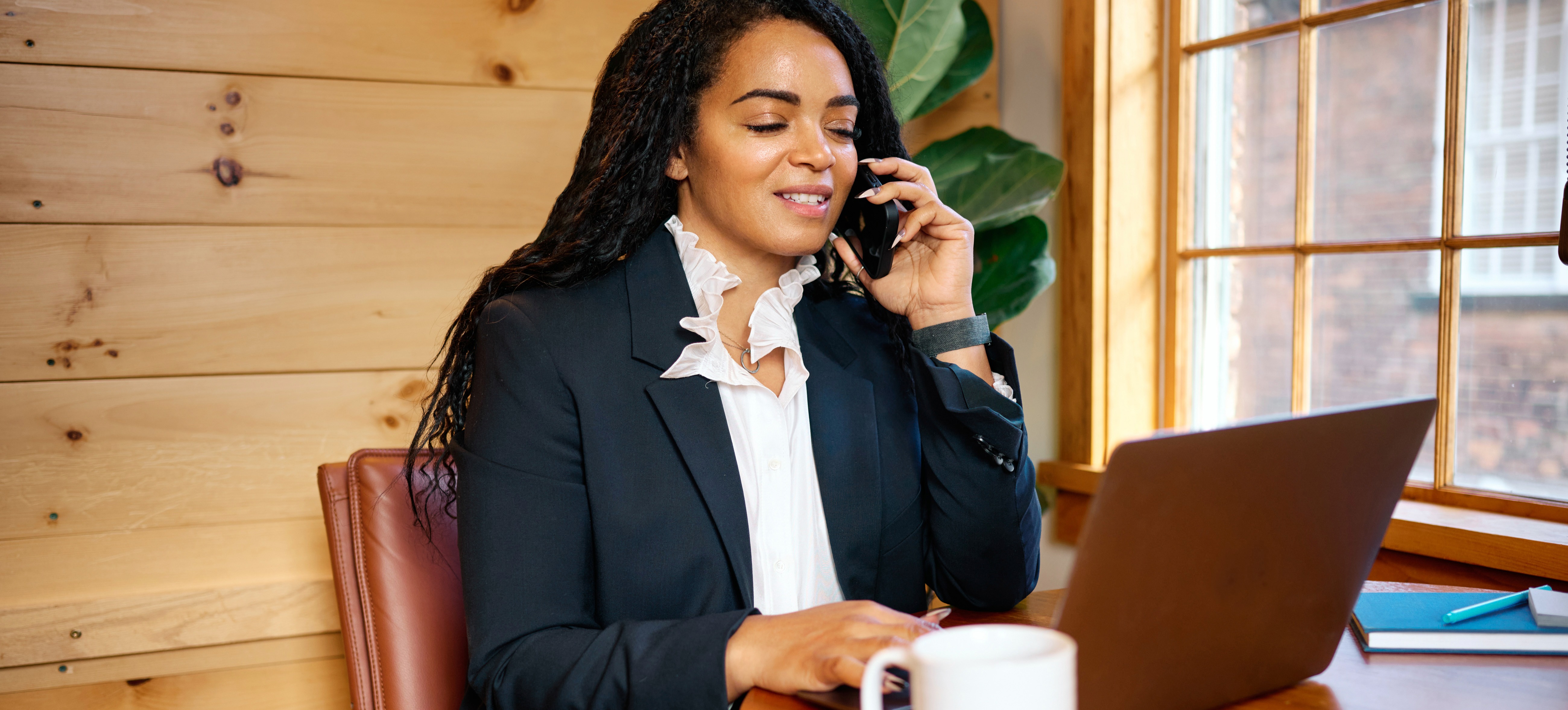 [Featured Image] A marketing professional works on creating a cold outreach email template on their laptop in a wood-paneled coffee shop. 
