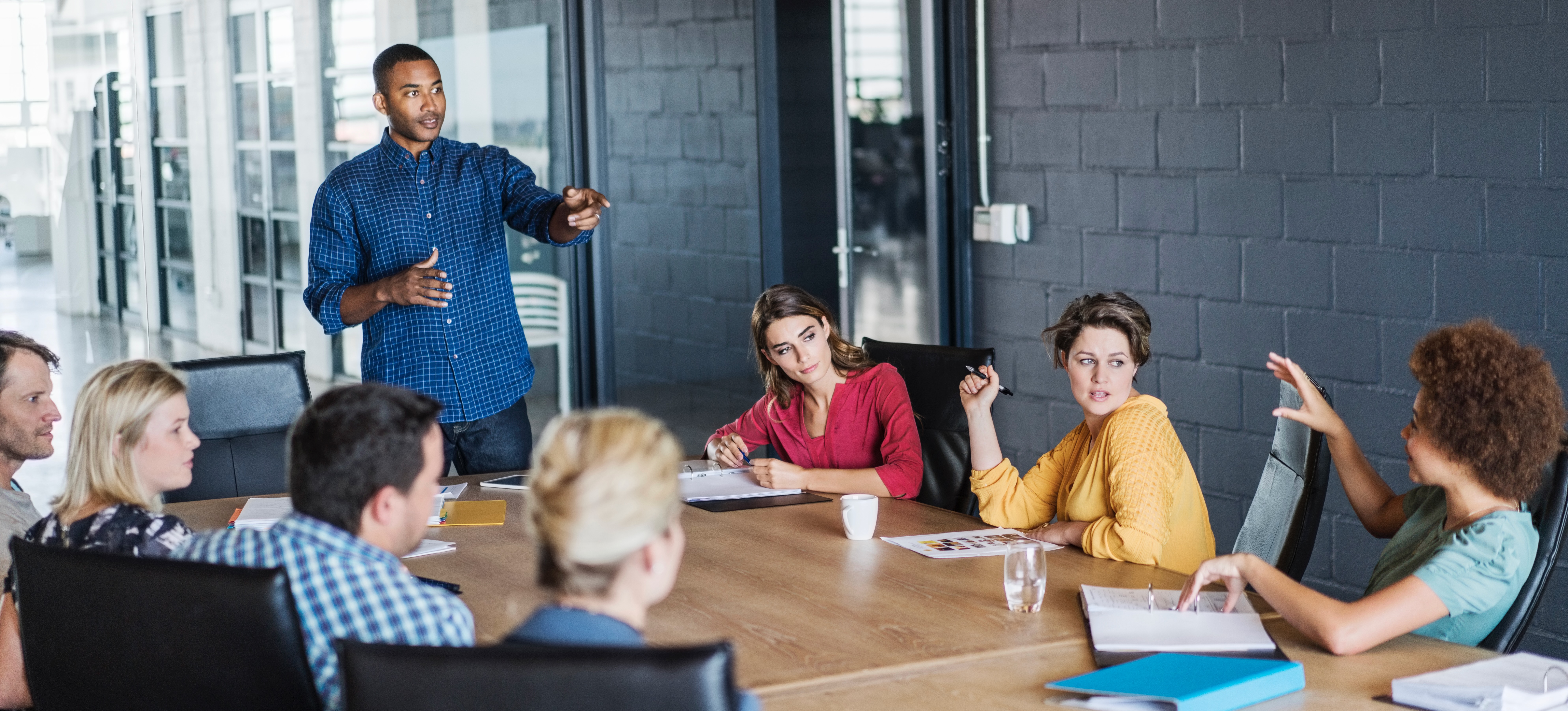 [Featured Image] Employees are at a conference table discussing a competency mapping strategy for their business.