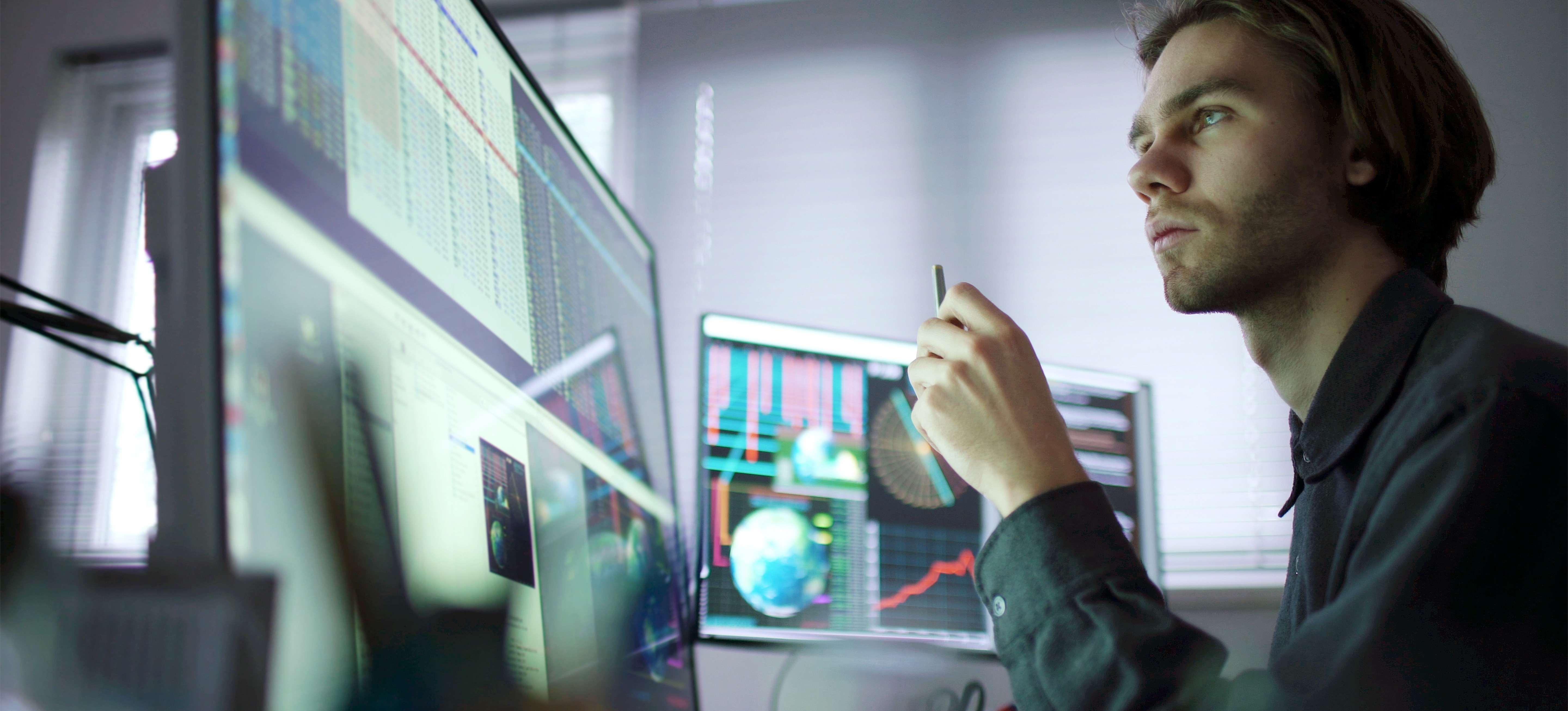 [Featured Imaga] A quality assurance specialist analyzes data on their desktop computer screen with a pen in their hand.
