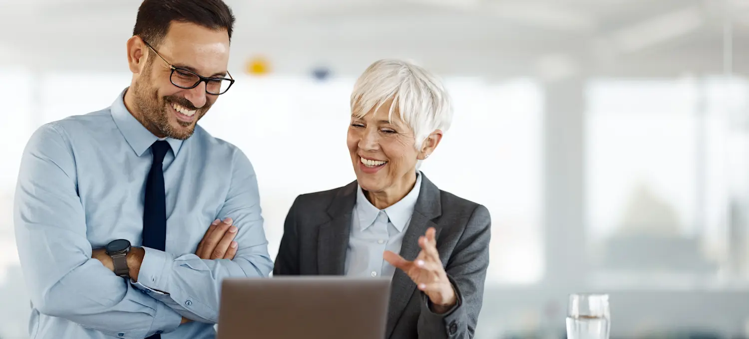 [Featured Image] Two corporate colleagues discuss the company’s organizational leadership and how to develop leadership skills as part of their company-wide professional development program.
