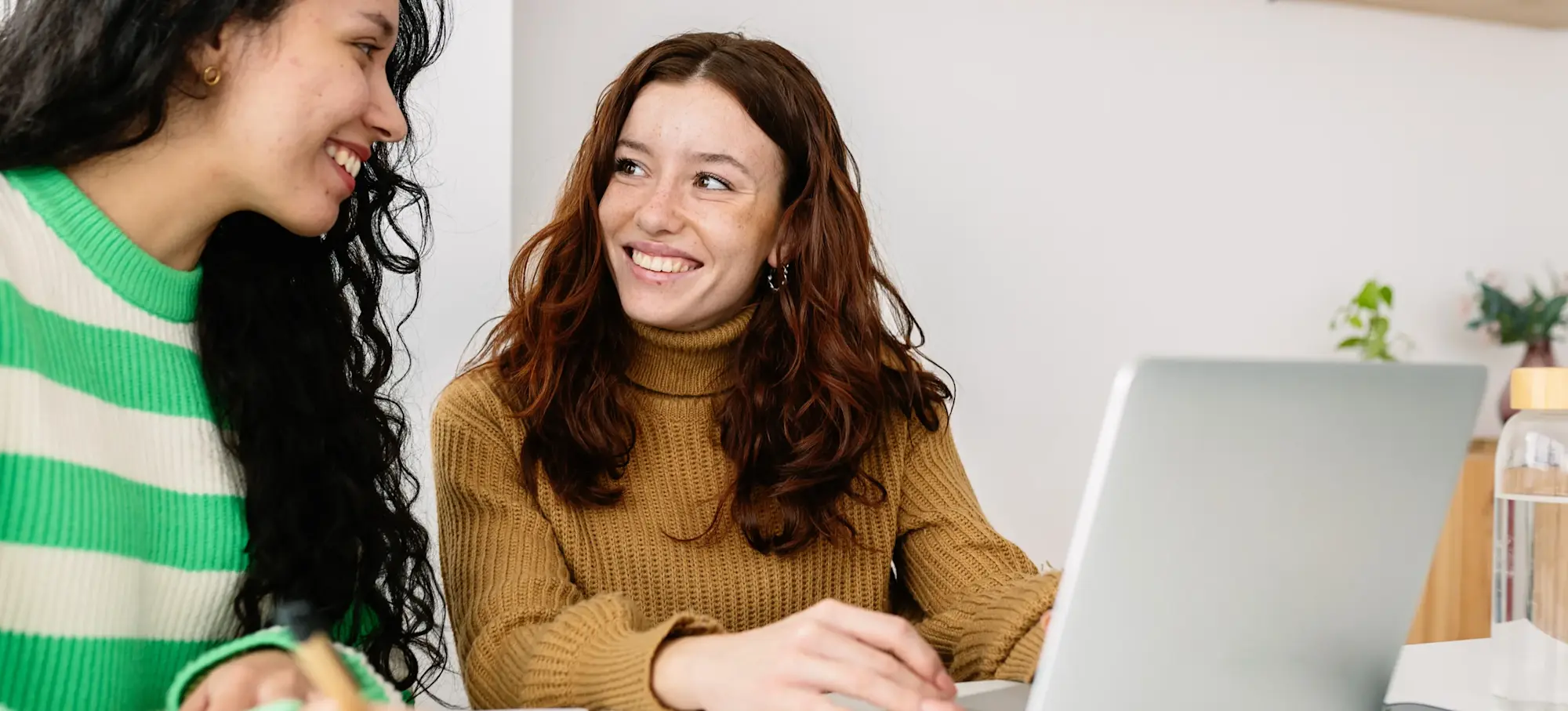 [Featured image] Two learners sit in front of a laptop and discuss whether to use Python or C# for a project.
