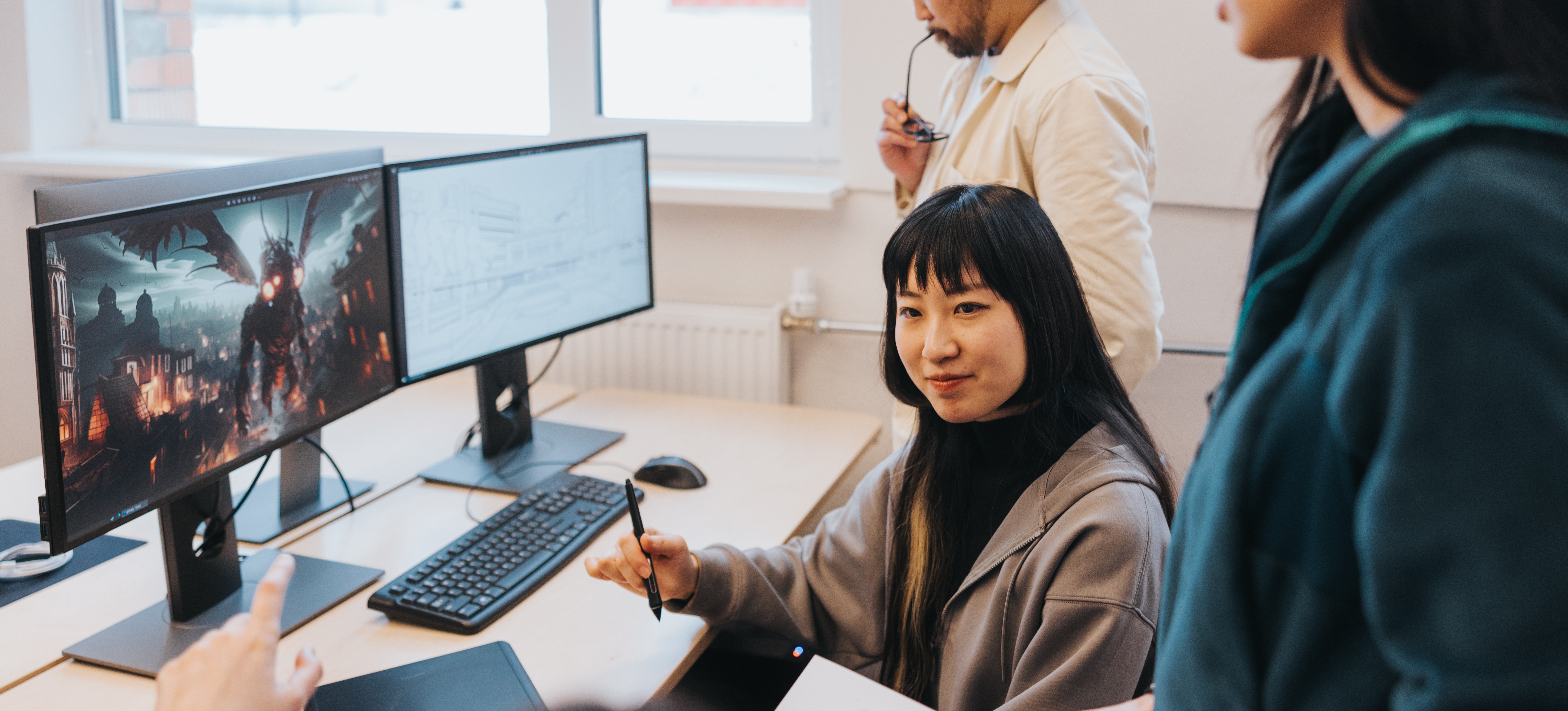 [Featured Image] A team of video game developers discuss a new project that's displayed on a computer screen.
