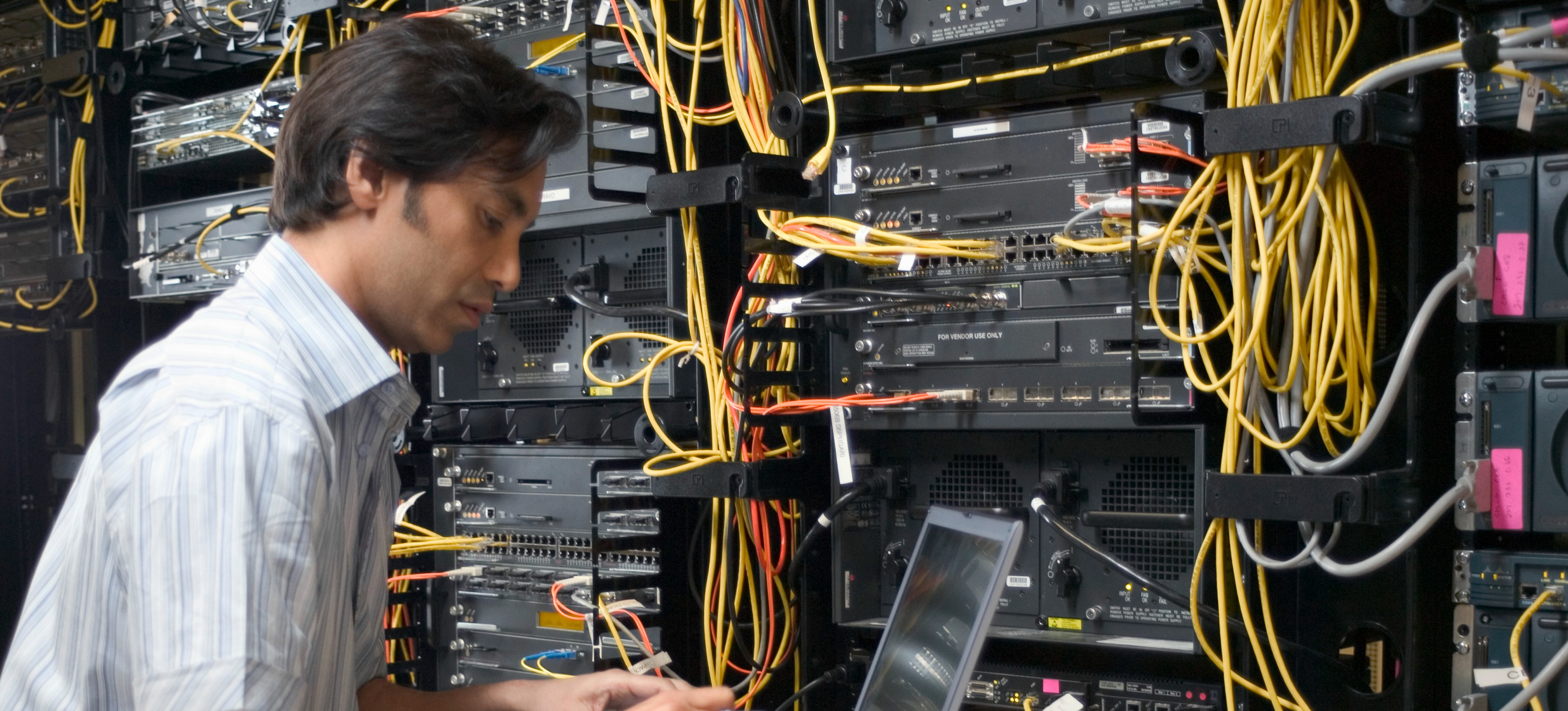 [Featured Image] A big data installer is working in a server room.