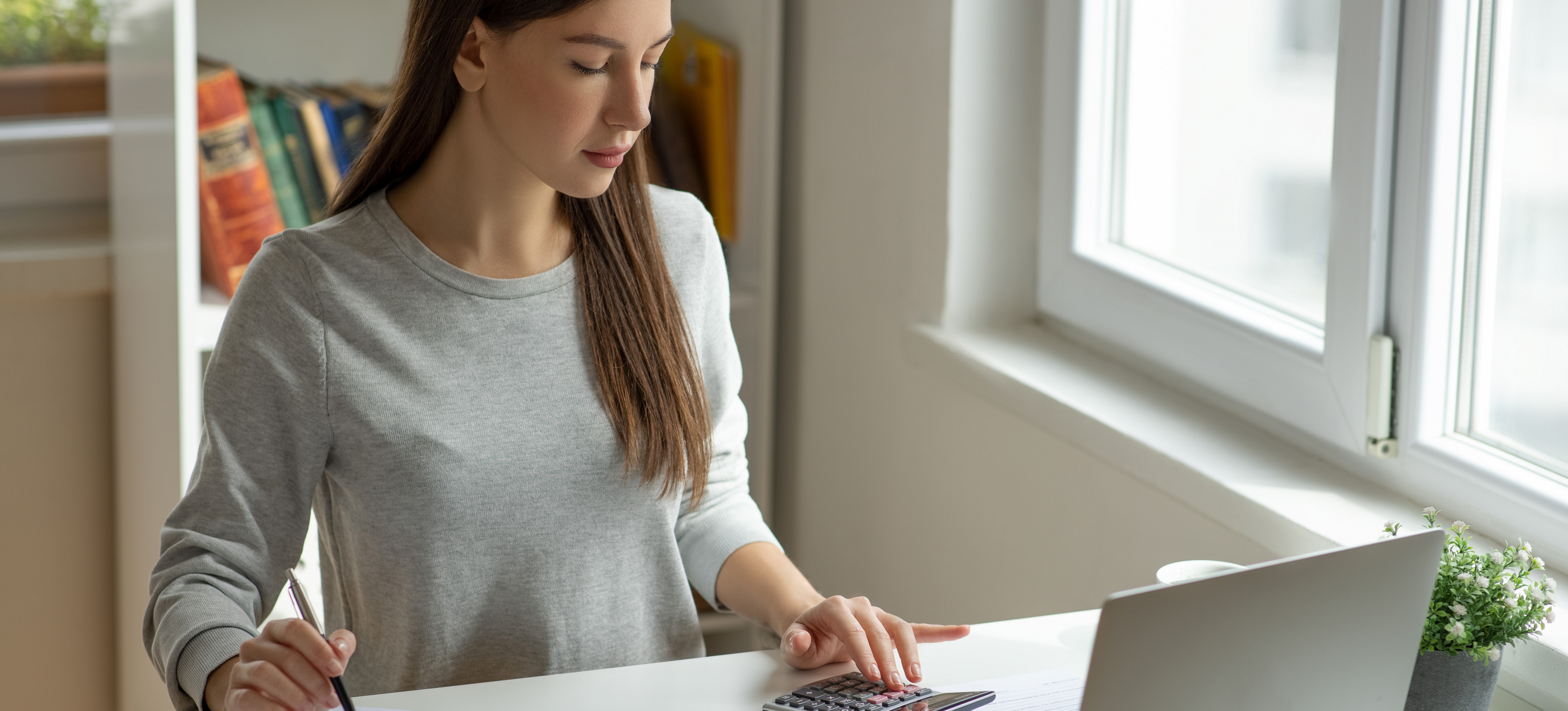[Featured Image]: A person sits at a desk and determines what is net pay before putting together a monthly budget.

