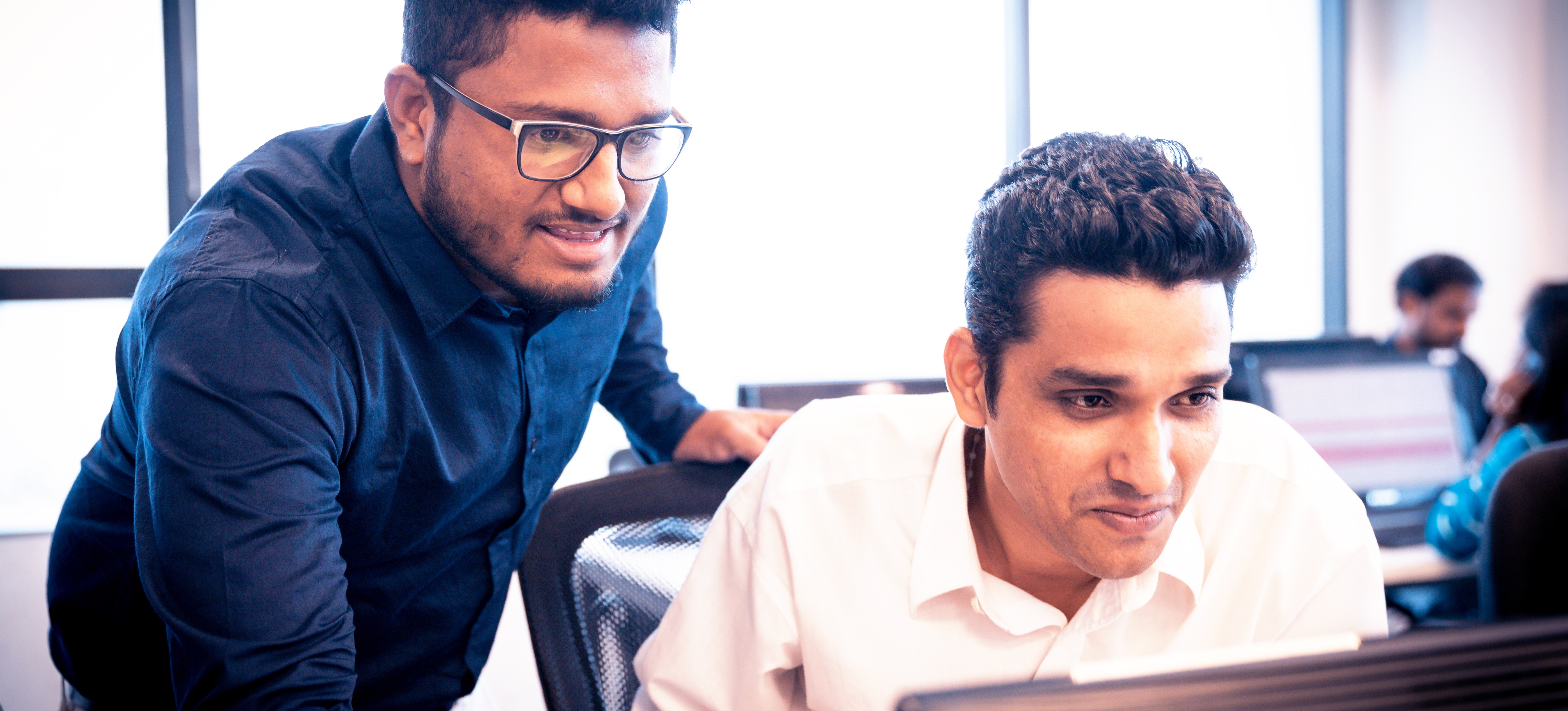 [Featured image]: Two engineers discuss machine learning vs AI as they work at a computer.
