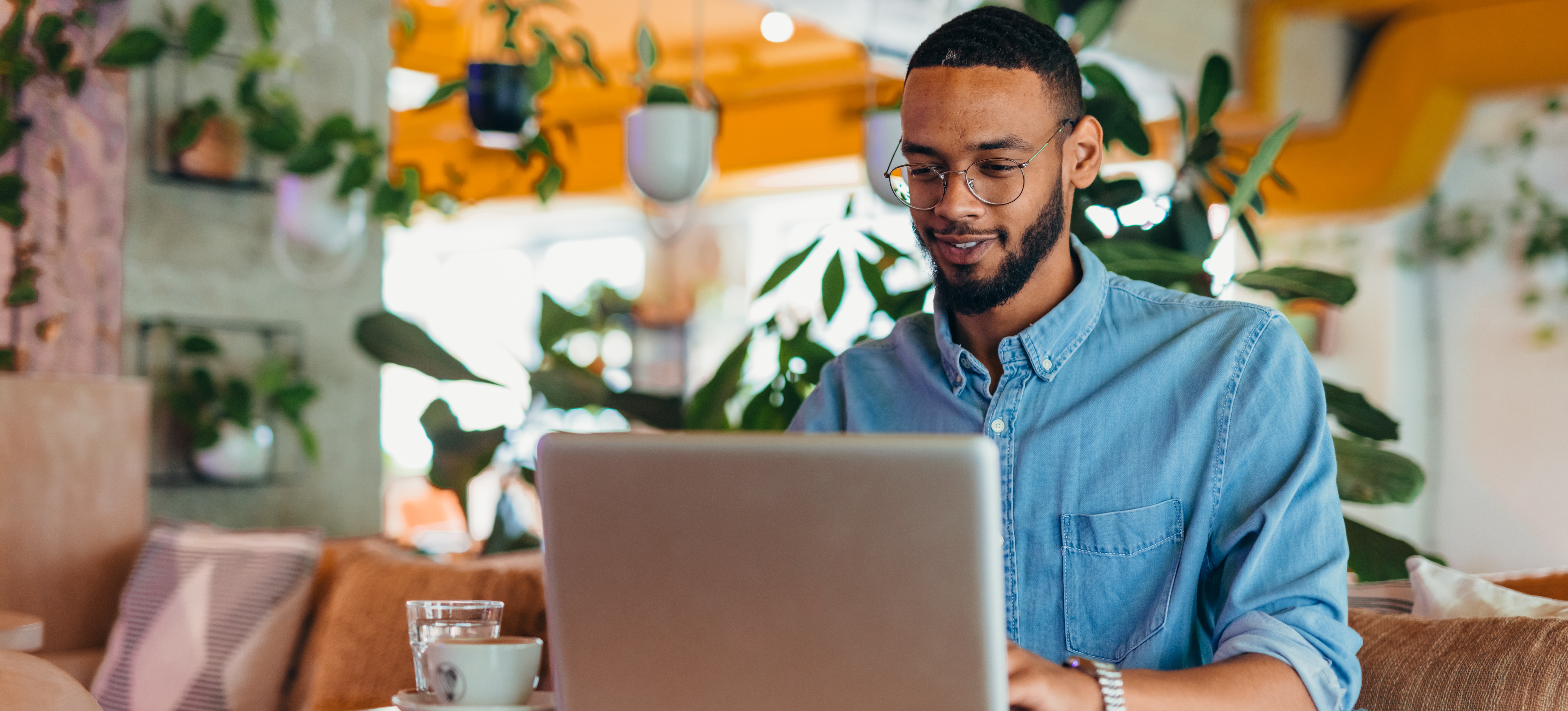 [Featured Image] A smiling person sits in a brightly lit cafe surrounded by hanging plants and works at their laptop with GPT-4.