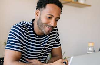 [Featured image] A man sits at a laptop in his home and explores a potential Linux career path for his future.
