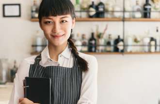 [Featured image] A college student working part-time in a cafe wears an apron and holds a menu.