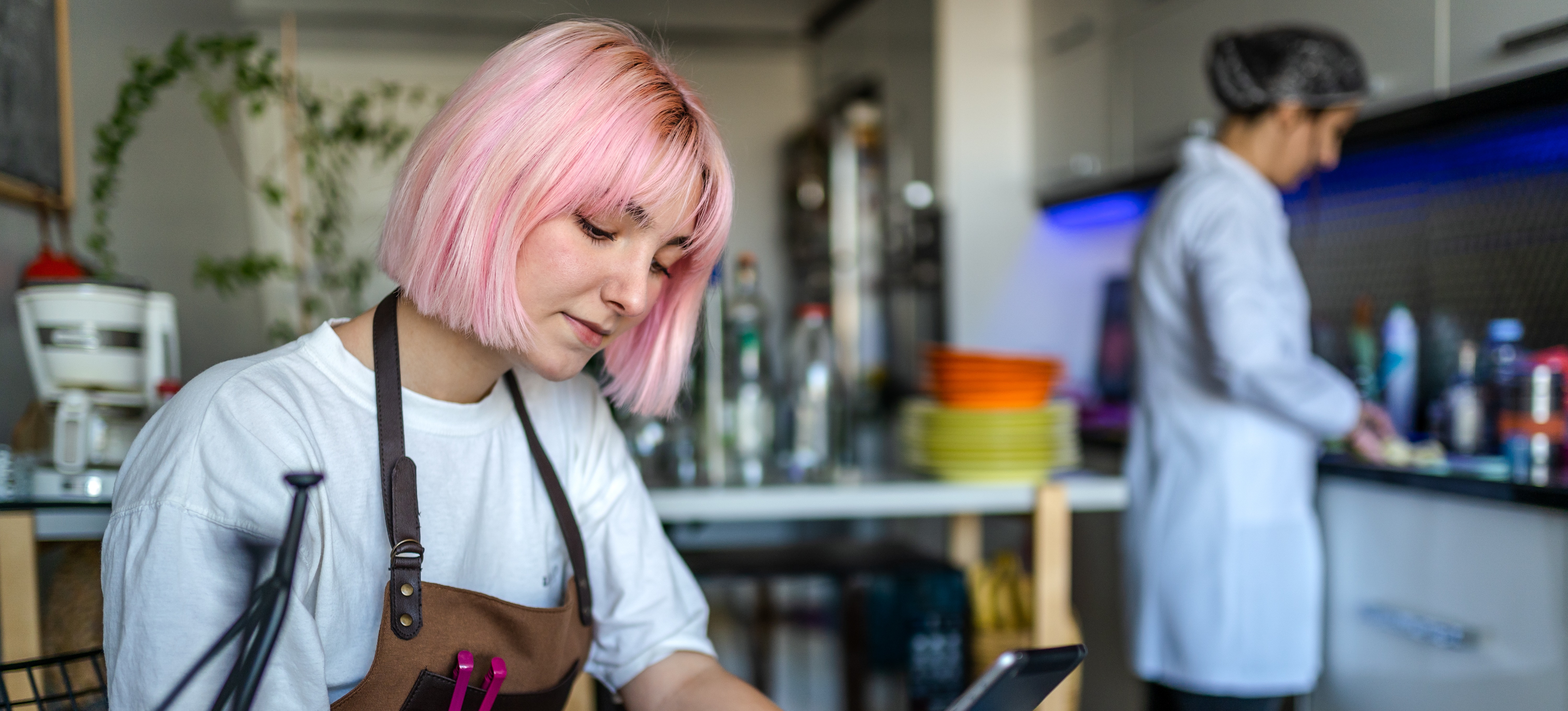[Featured Image] A college student prepares for an exam while working a part-time job in a cafe on campus.
