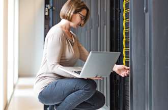 [Featured image] An employee holding a laptop visits her company's big data storage warehouse.