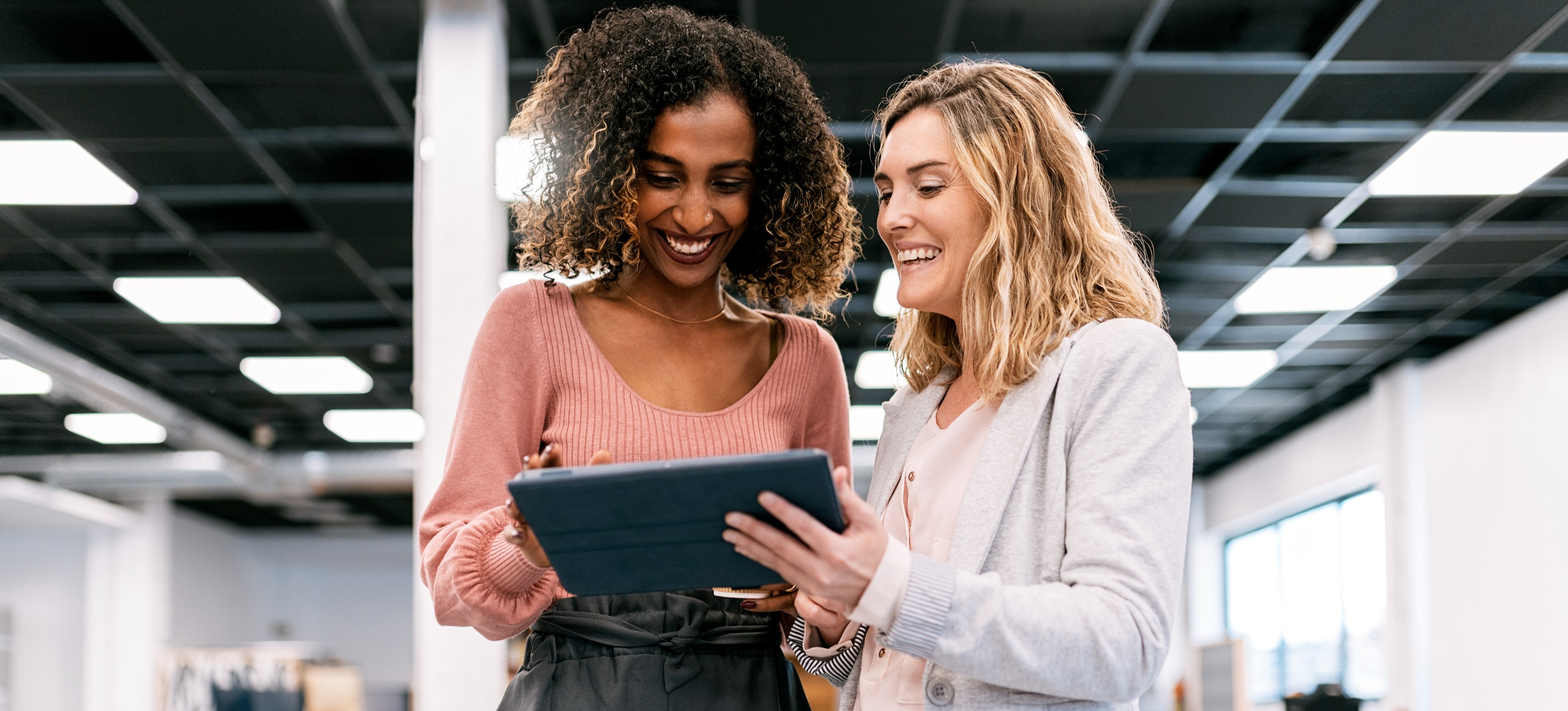 [Featured Image] Two health care data analysts review public health informatics on a tablet.