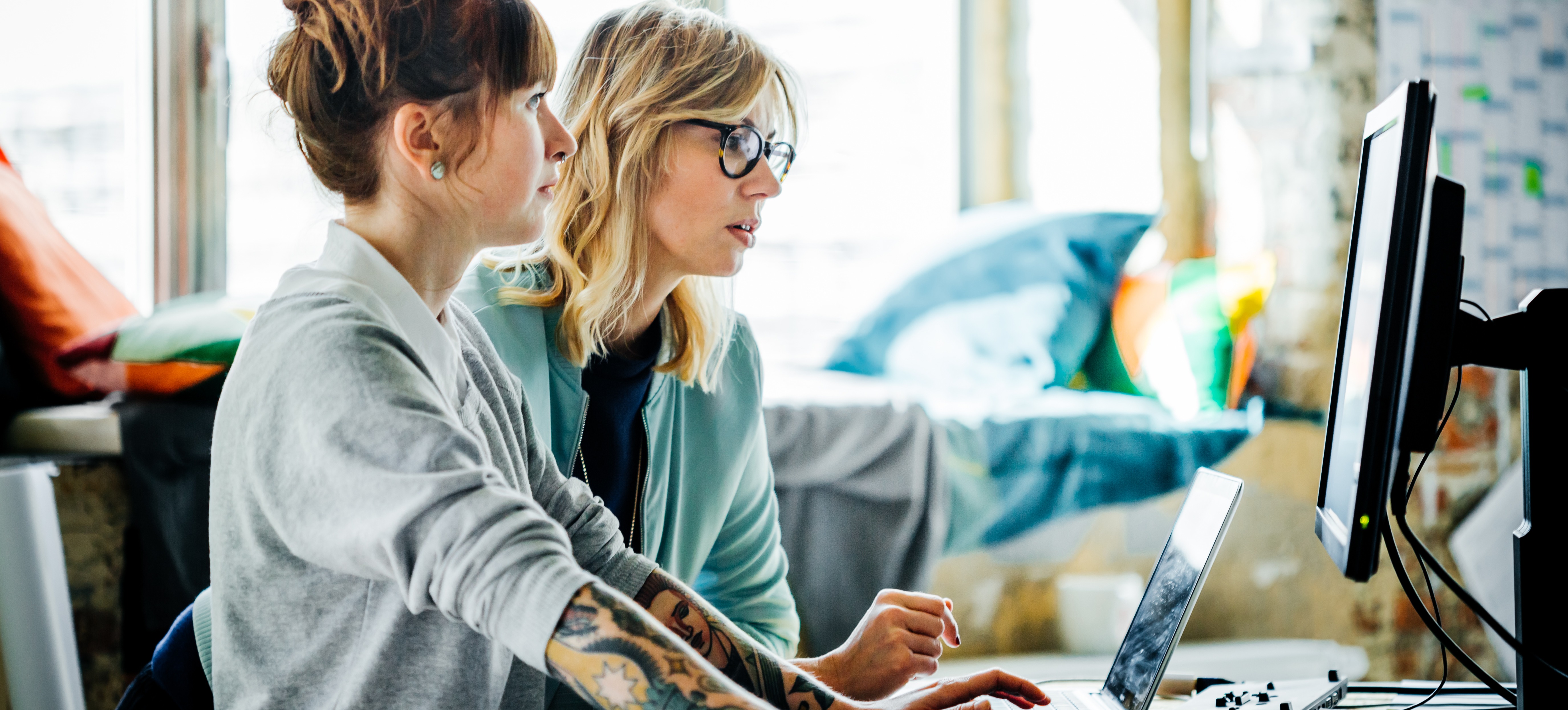 [Featured image] Two people in tech jobs collaborate in front of a computer.