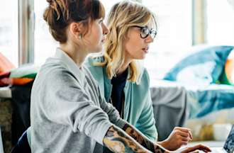 [Featured image] Two women in tech jobs collaborate in front of a computer.