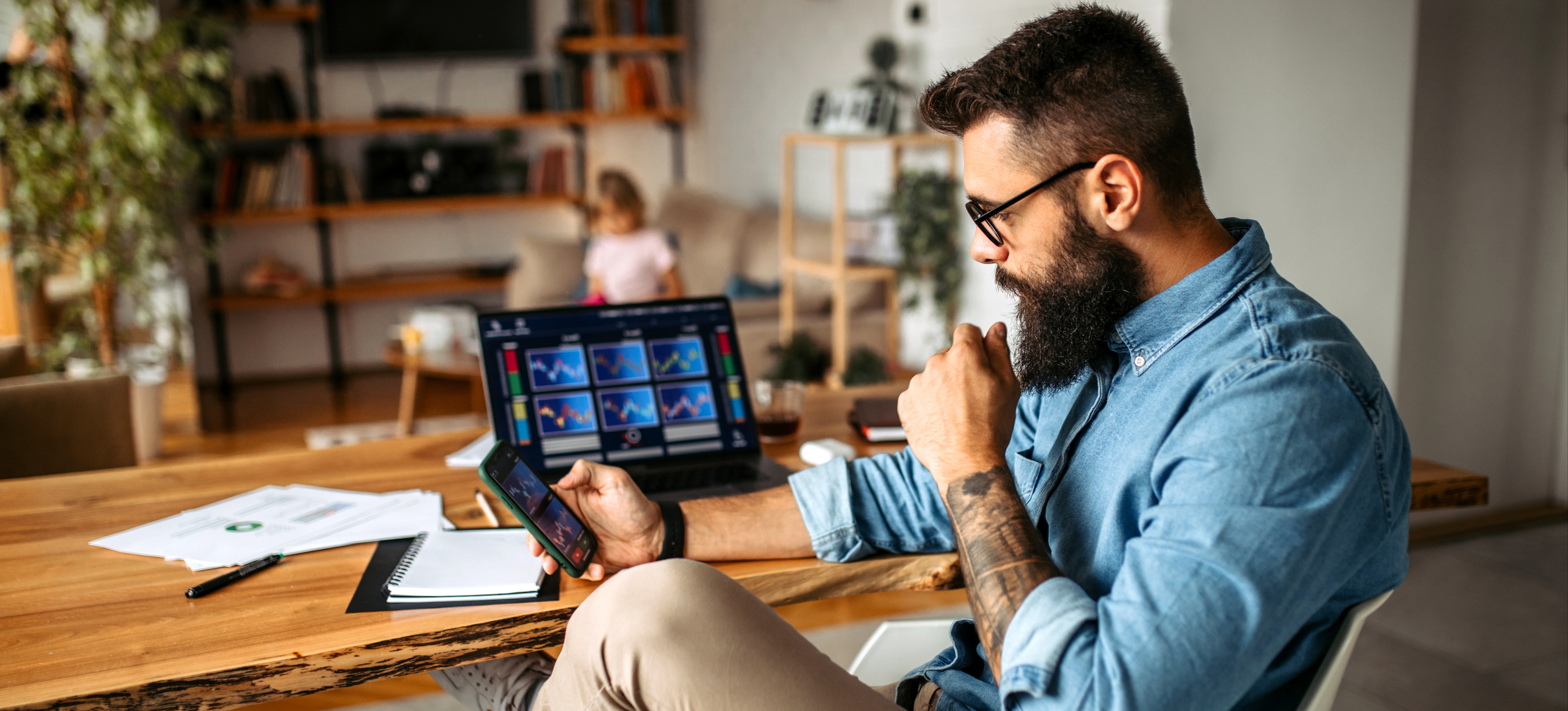 [Featured Image] A man is sitting in his home office working on cryptocurrency trading.