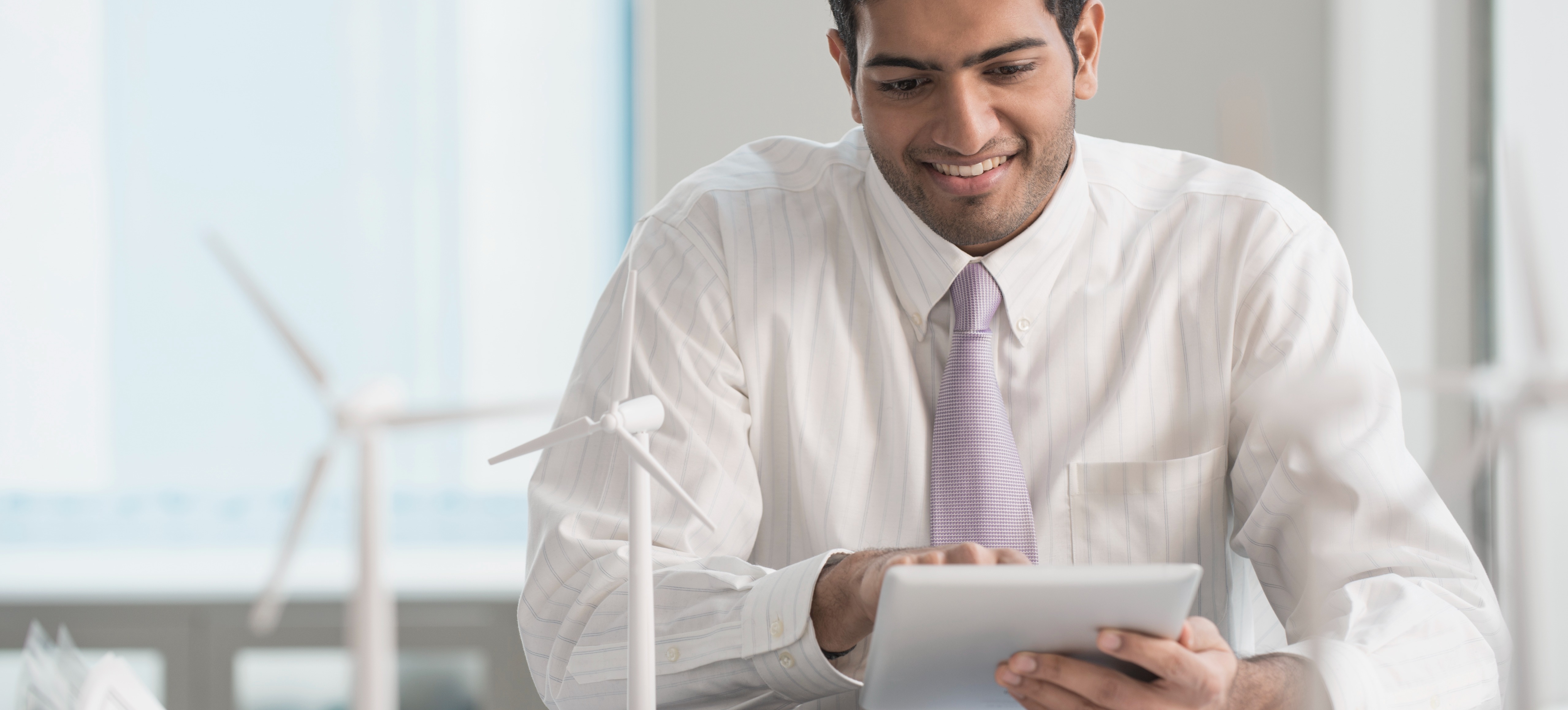 [Featured Image] A businessman sits at his desk and uses his device to consider the meaning of SDE full form.