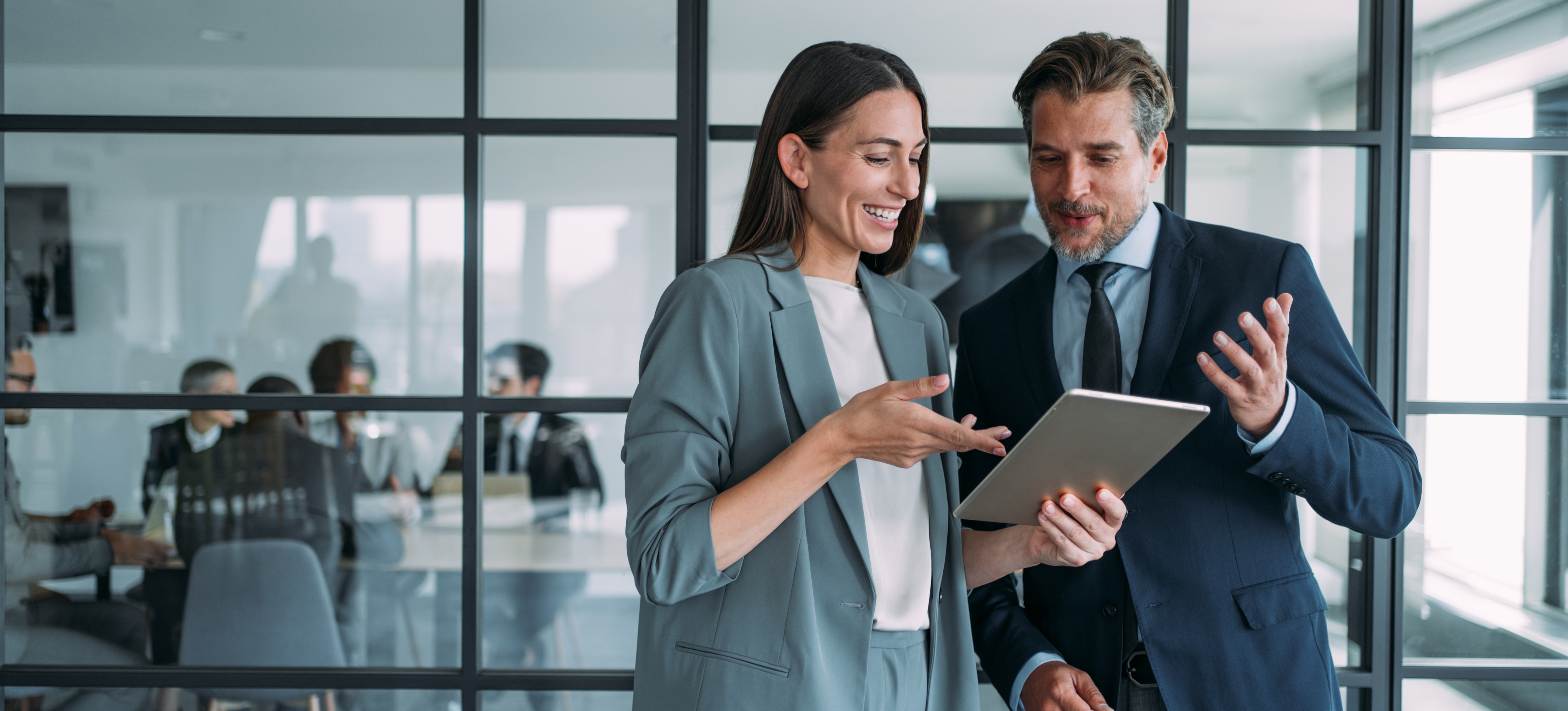 [Hauptbild] Zwei Führungskräfte diskutieren in einem Büro vor einer Fensterfront über die Bedeutung von EVP, also dem Employee Value Proposition (Mitarbeiterwertversprechen).