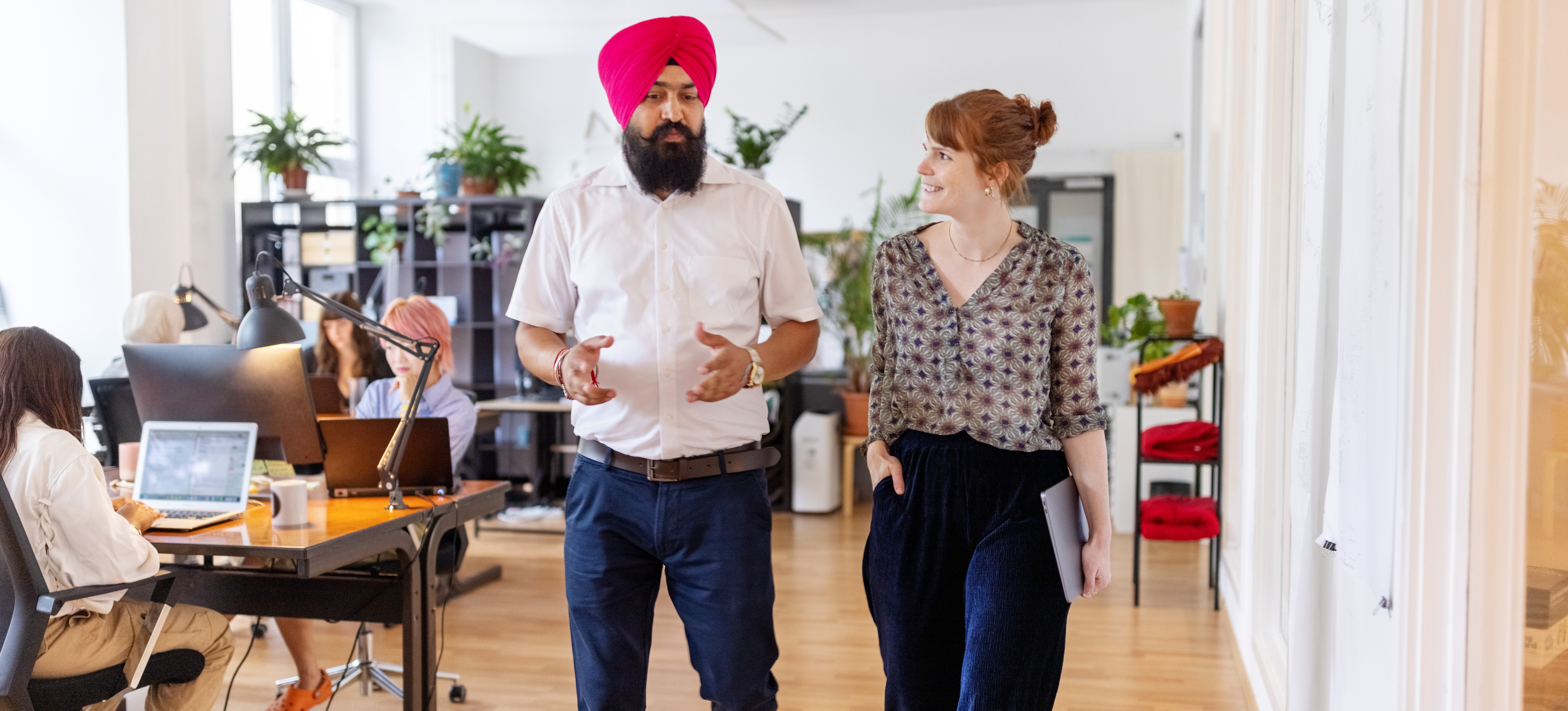 [Featured Image] Coworkers walk whilst discussing how to set boundaries at work.
