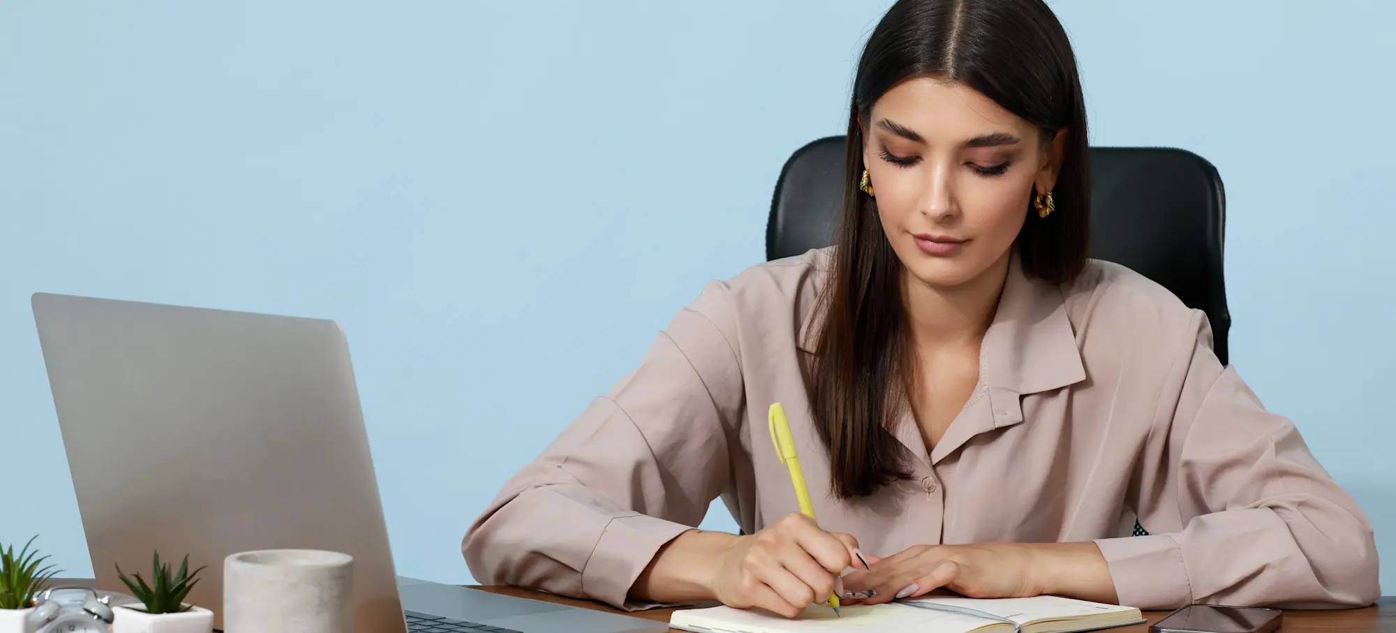 [Featured Image] An AI ethicist works at their desk with a laptop and notebook, ensuring their company's projects meet moral and social standards.
