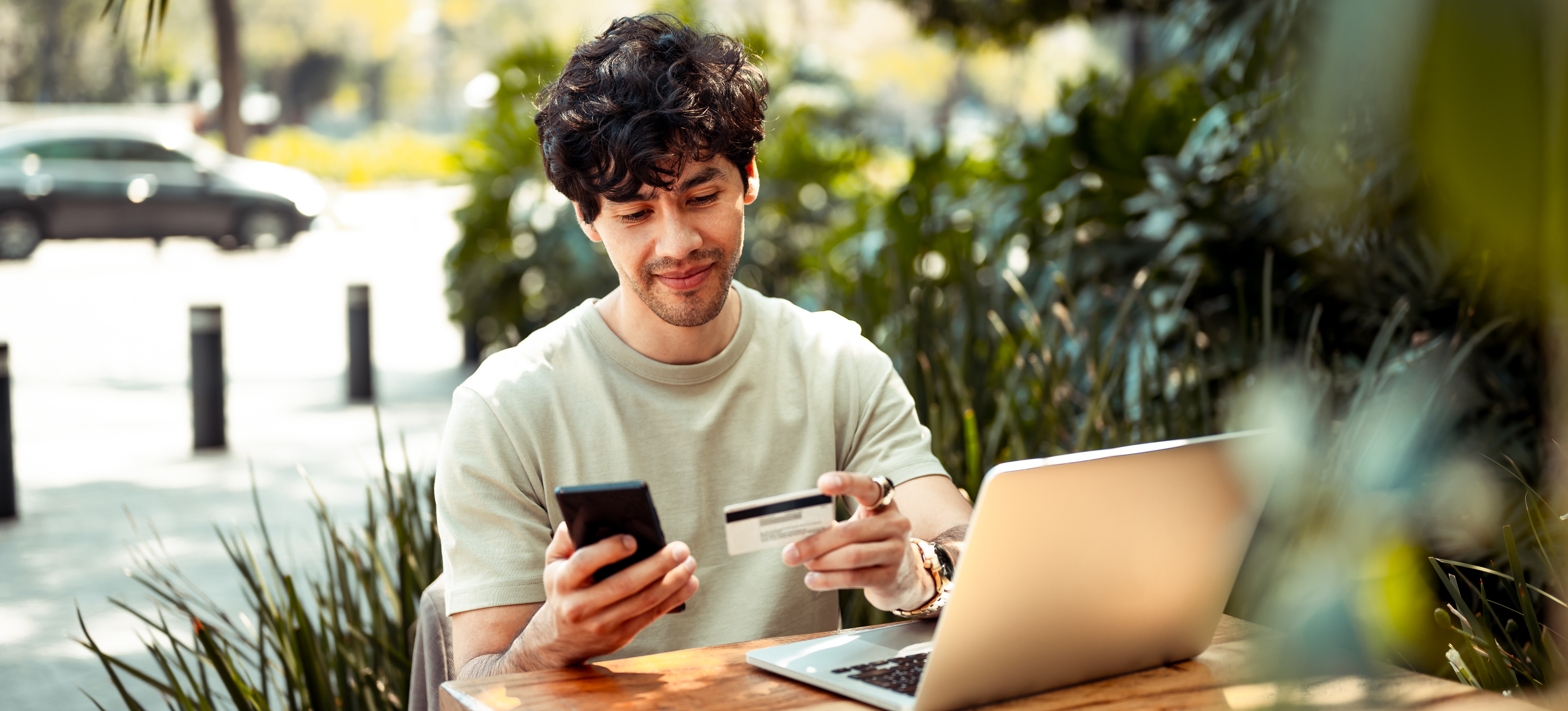 [Featured image] A business owner sitting at an outdoor cafe is adding Instagram Shopping to their Shopify store while using a laptop and smartphone and testing the store with a credit card.