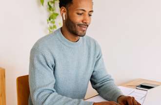 [Featured Image] A man works on his laptop in his home office using Power Query to manipulate data. 
