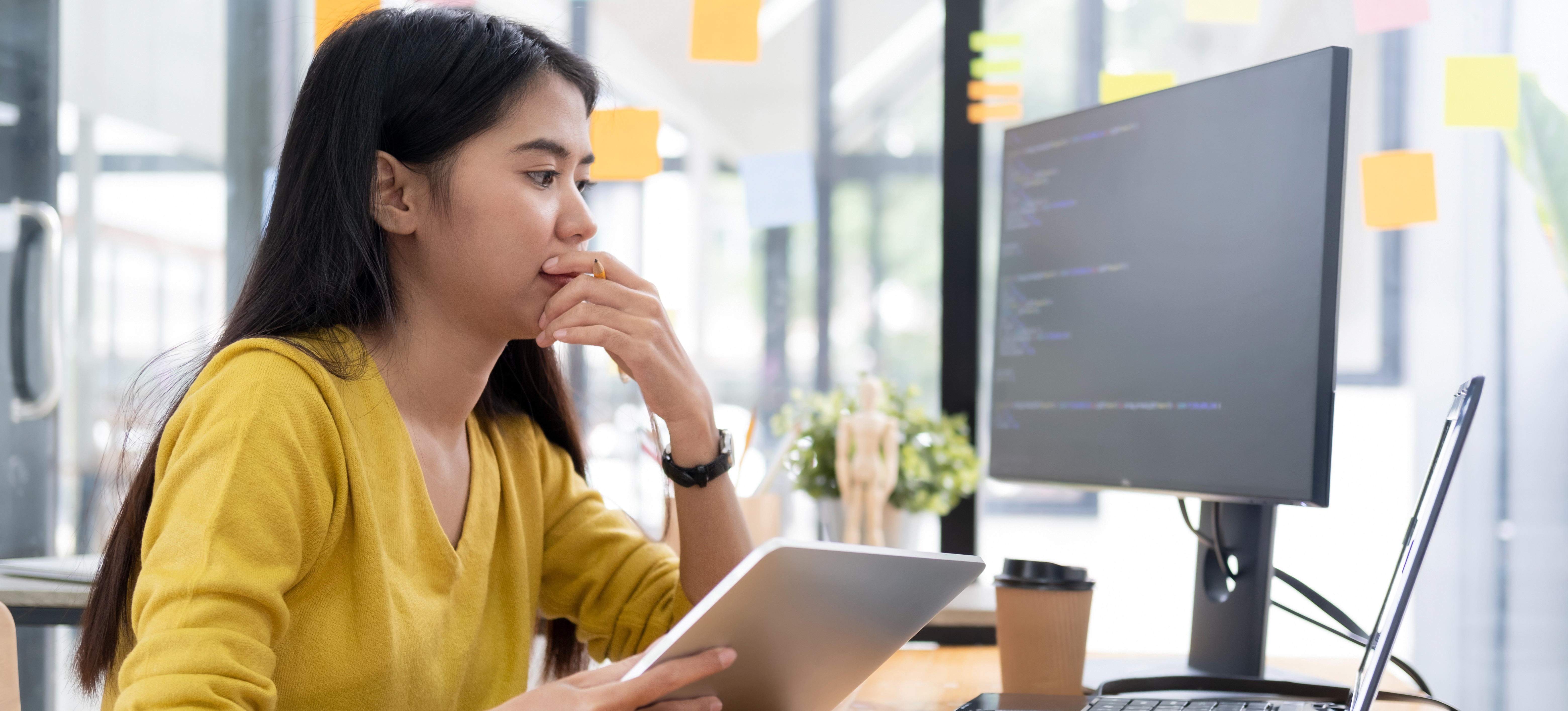 [Featured Image]: A person in front of a computer holds a tablet and contemplates, "Is computer science a good major?"
