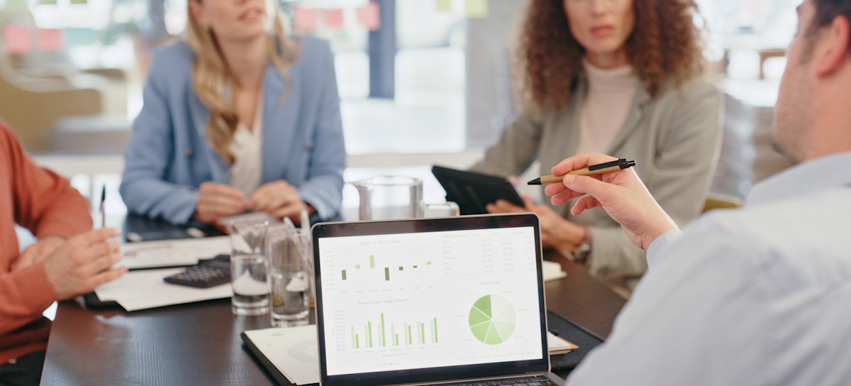 [Featured Image] Four co-workers sit around a table discussing their business intelligence strategy.
