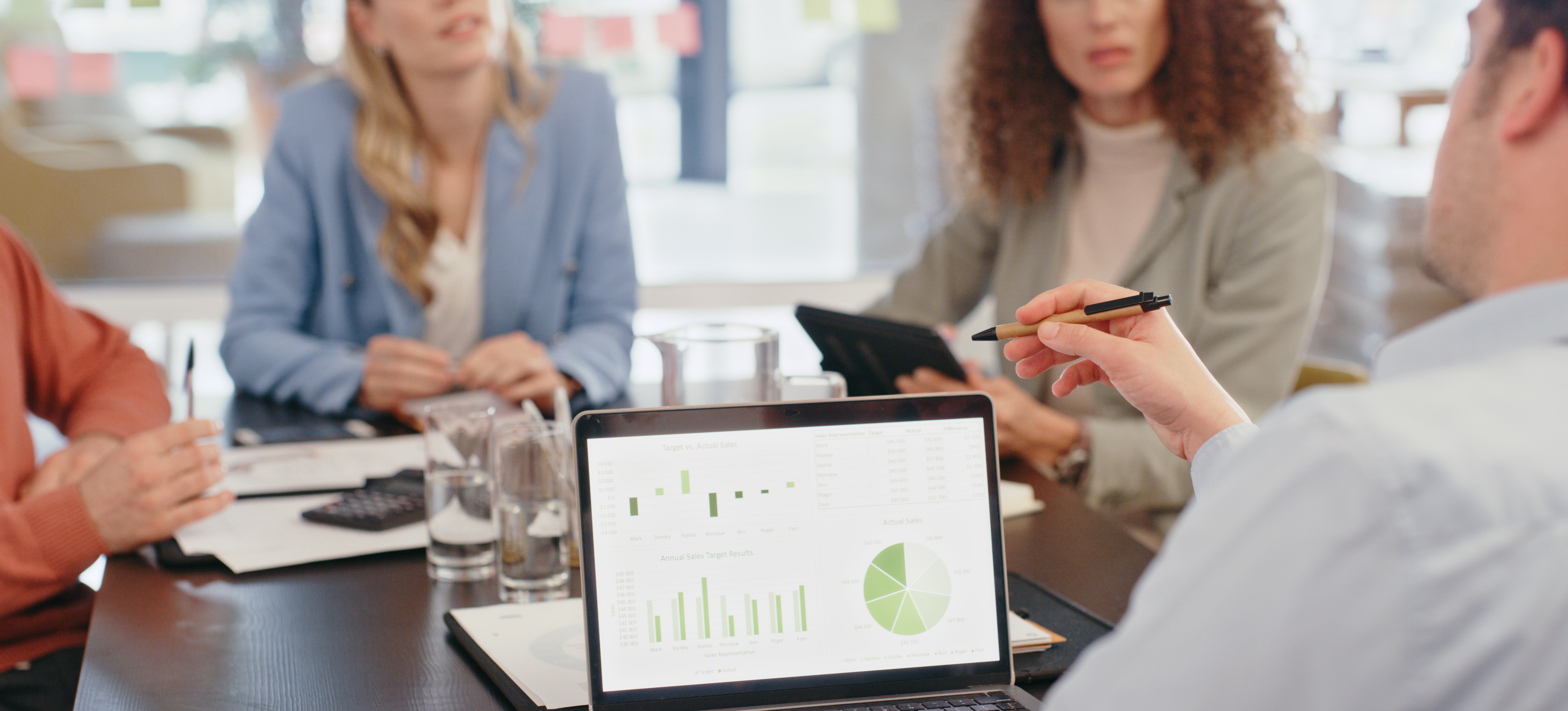 [Featured Image] Four co-workers sit around a table discussing their business intelligence strategy.
