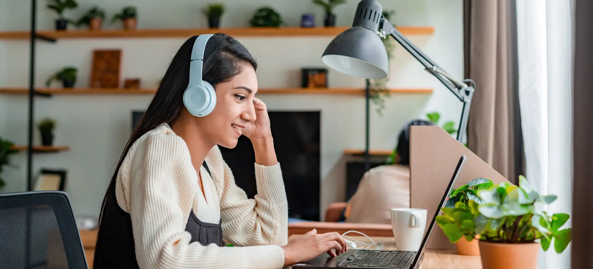 [Featured Image] A young learner wears headphones whilst engaging in online learning to immerse themself in the lesson. 