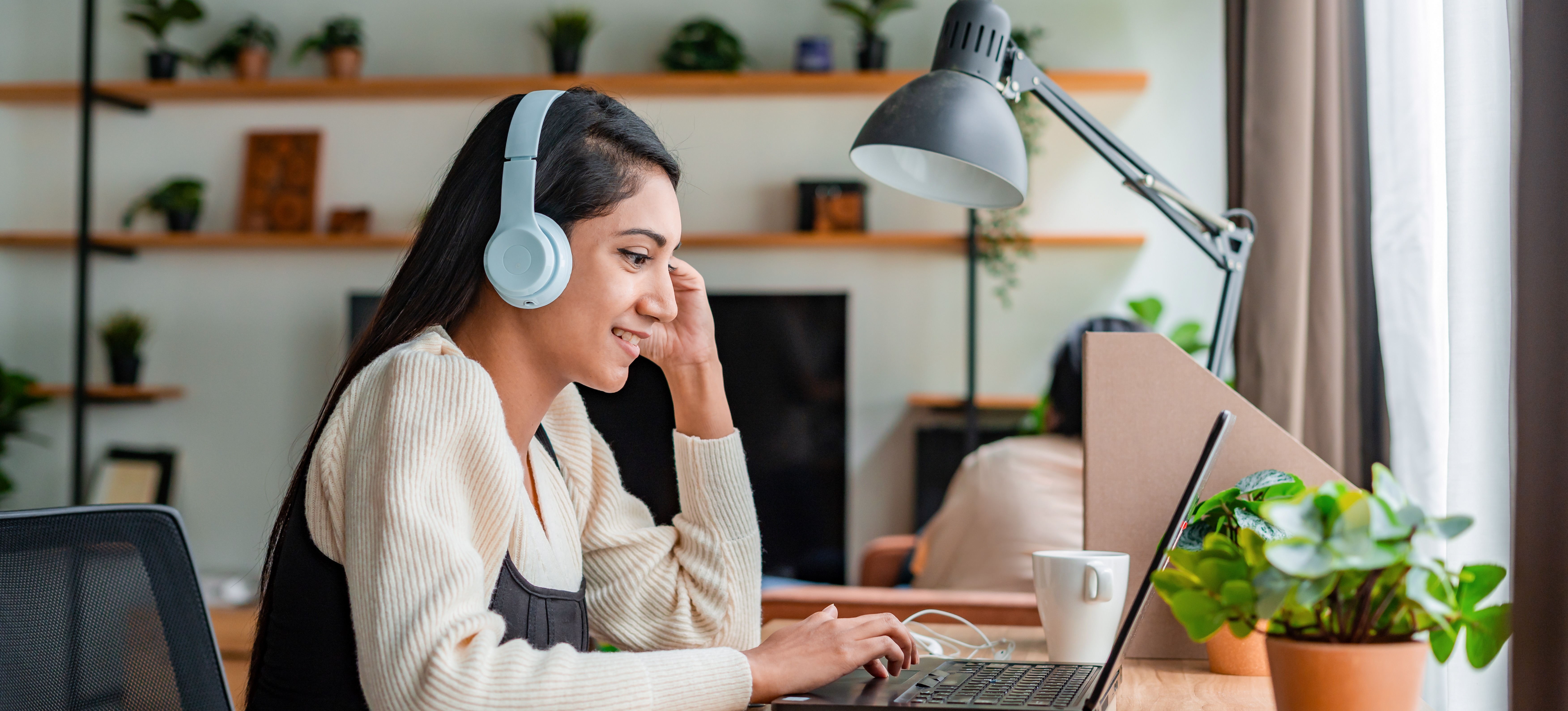 [Featured Image] A young learner wears headphones whilst engaging in online learning to immerse themself in the lesson. 