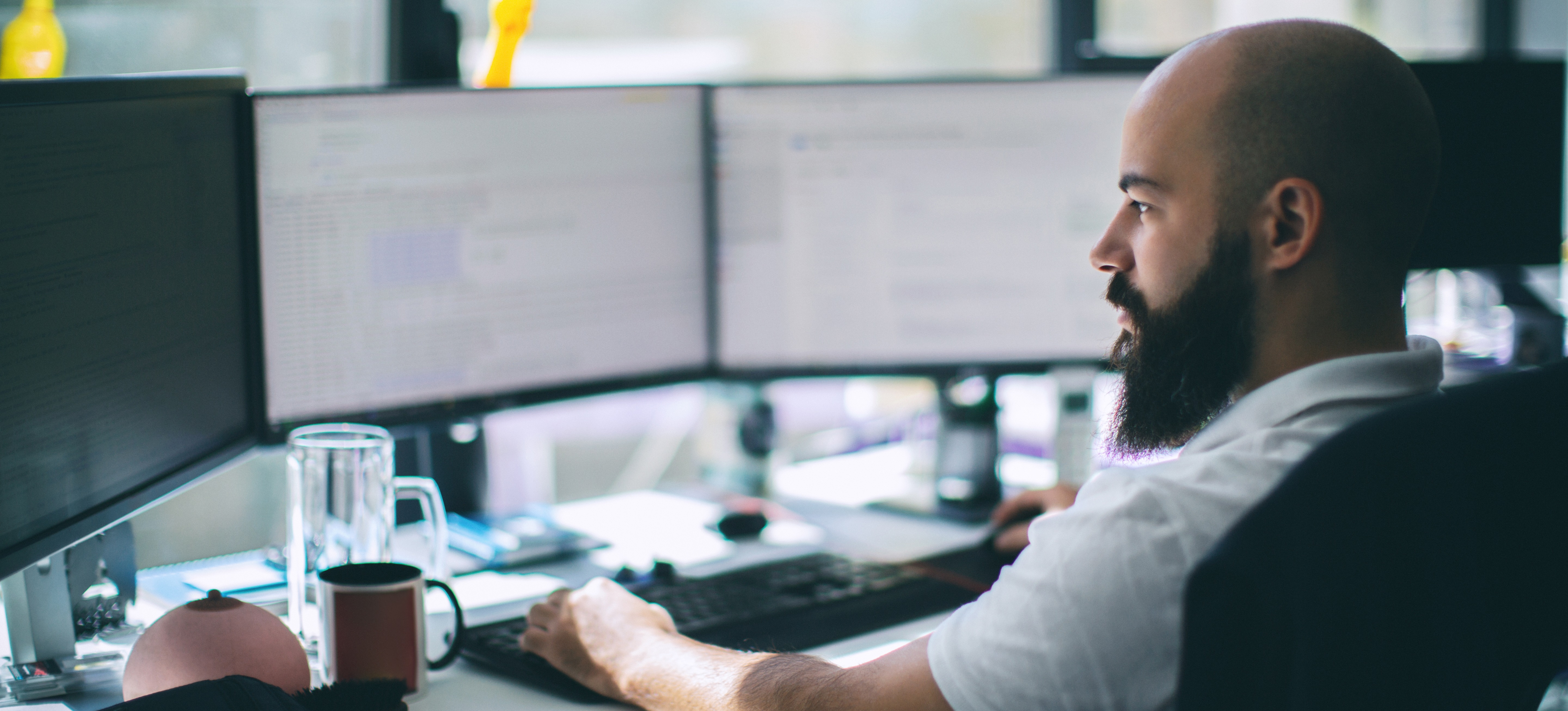 [Featured Image] A coworker sits at a table working with a device driver on their computer.