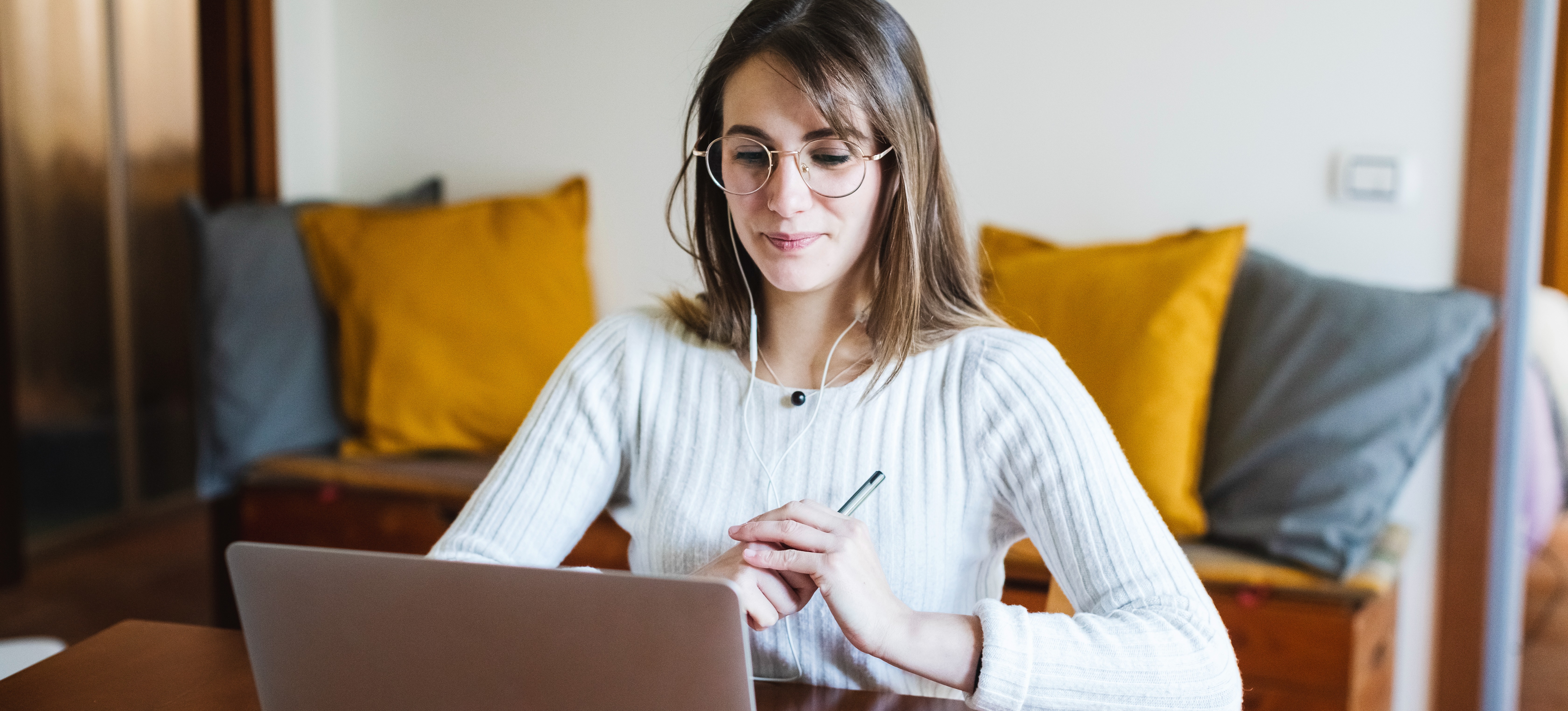 [Featured Image]: A law degree student wearing glasses and a white sweater sits in front of their computer screen and holding a pen.