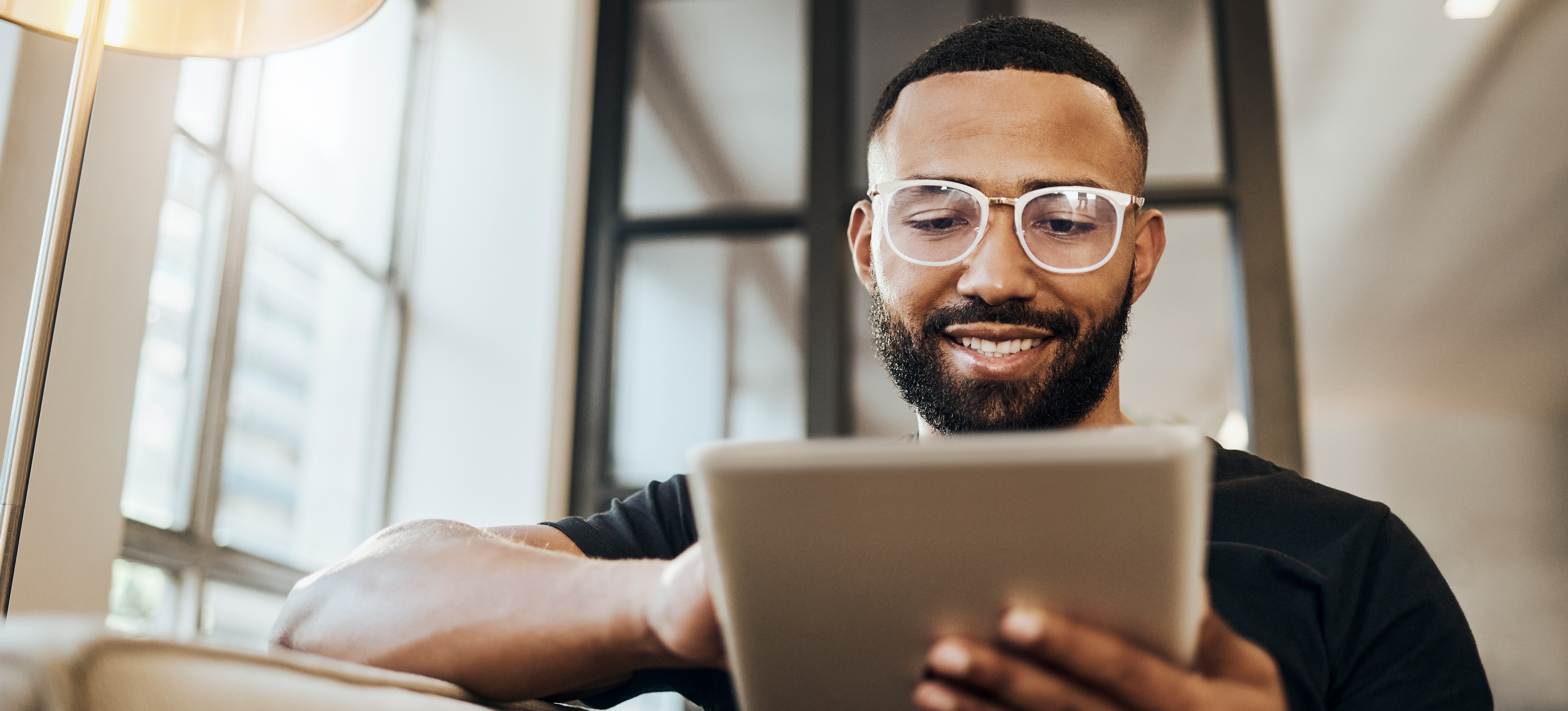 [Featured Image] A man sitting on a sofa in a home office analyzes his website's metrics after learning how SEO can bring more traffic to his site.
