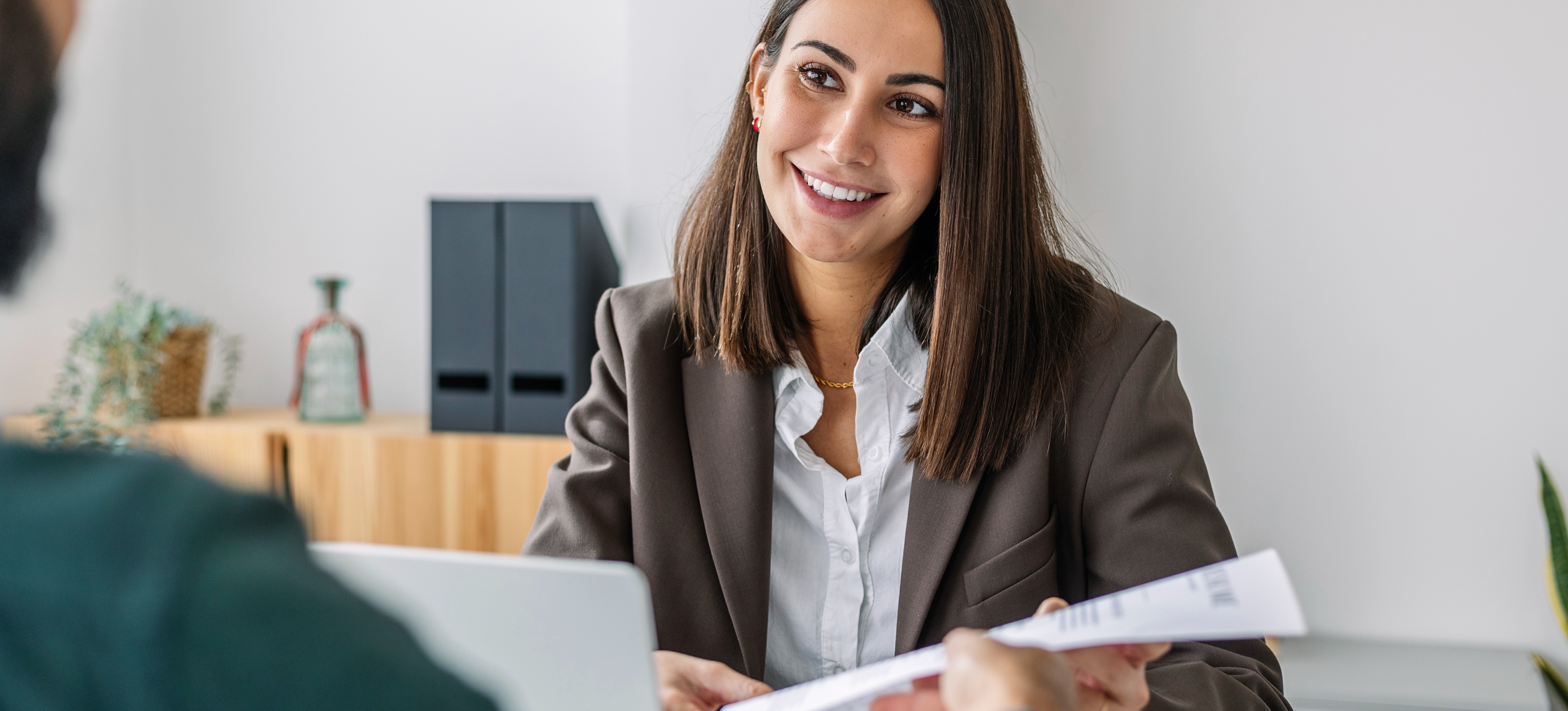 [FEATURED IMAGE] An interviewee hands their resume to a hiring manager as they embark on a job search.
