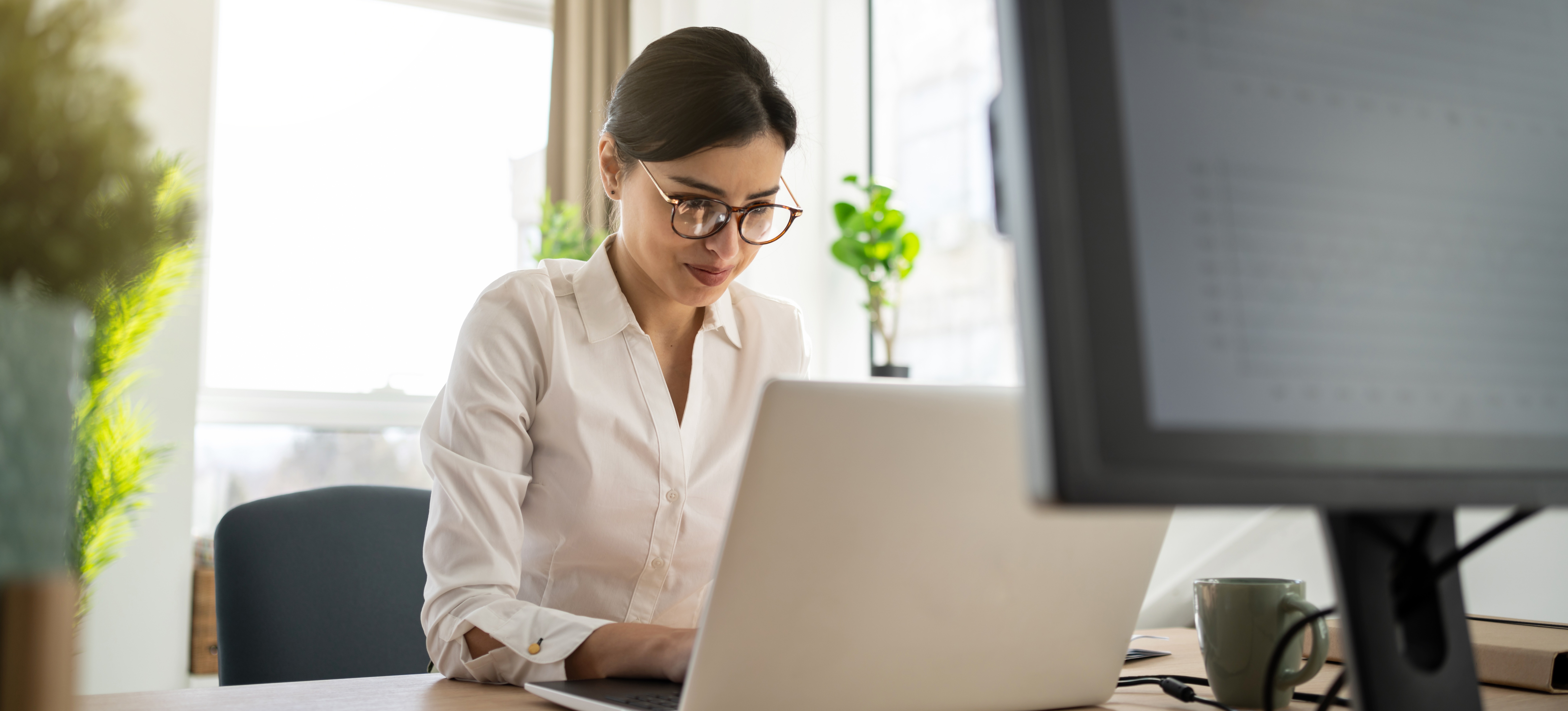 [Featured Image] A Certified Business Analyst Professional holder sits in her office contemplating as she works on her laptop.