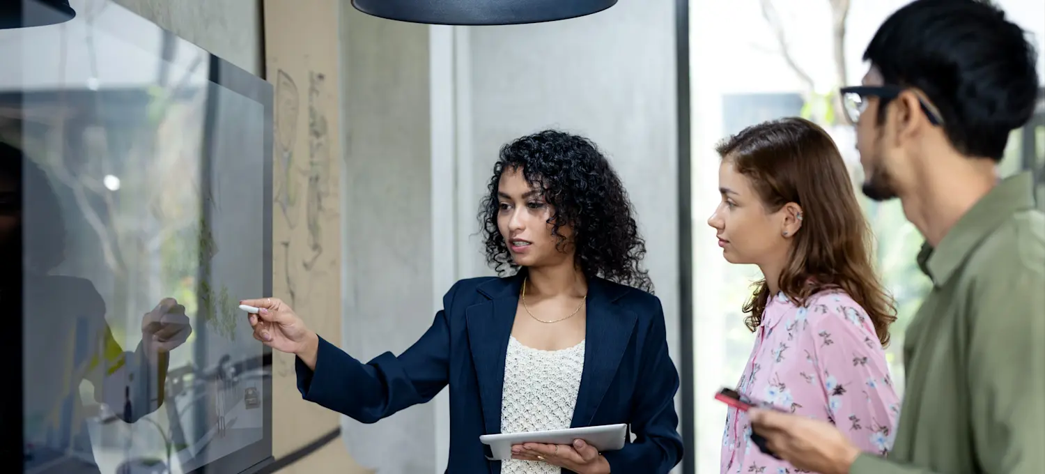 [Featured Image] A professional in a collaborative workspace, engaging with colleagues while analyzing data and discussing Lean portfolio management (LPM) strategies.
