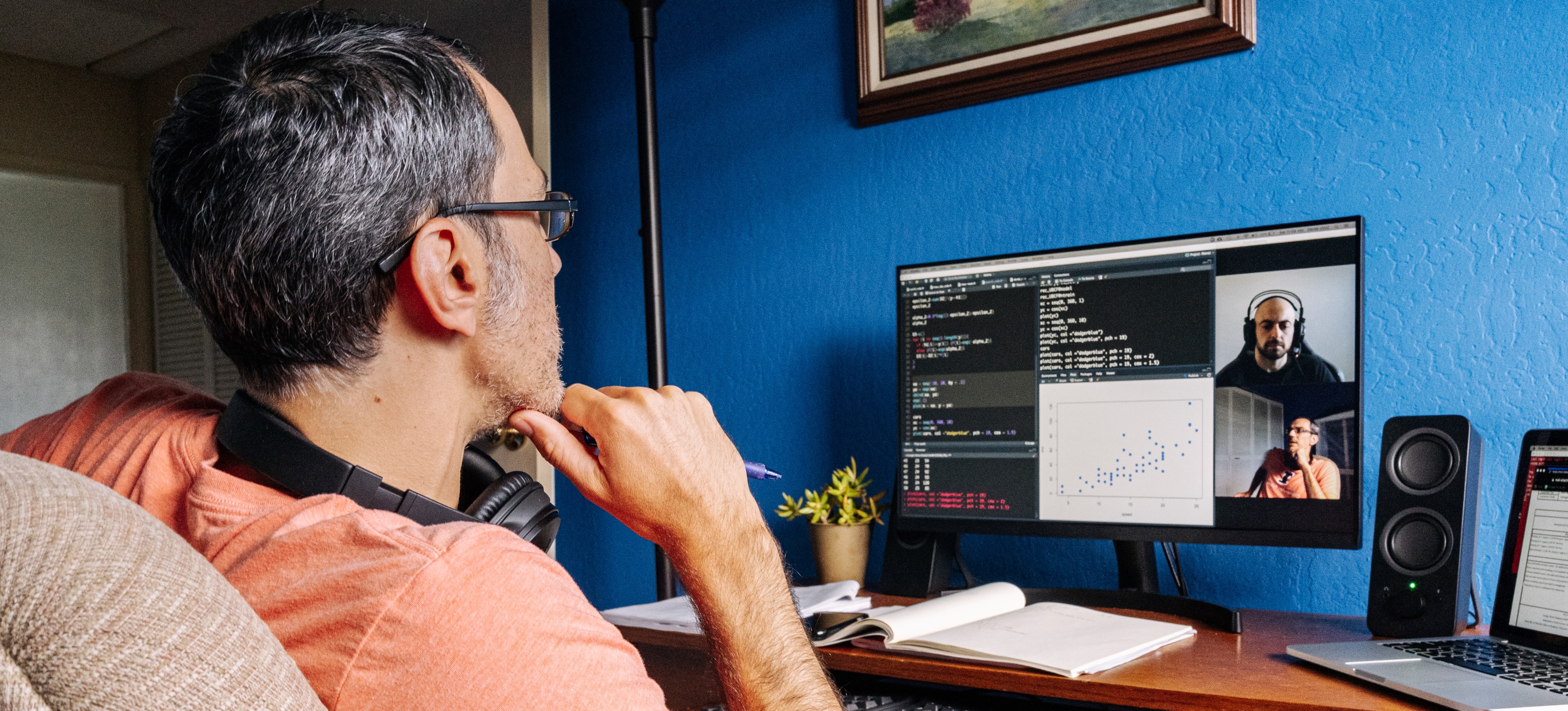 [Featured Image] A DevOps professional sits at a desk reviewing code on a video call with a software engineer.