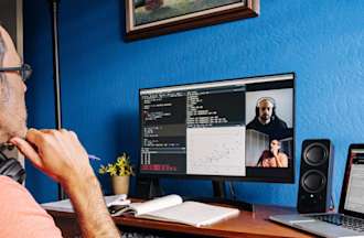 [Featured Image] A DevOps professional sits at a desk reviewing code on a video call with a software engineer.