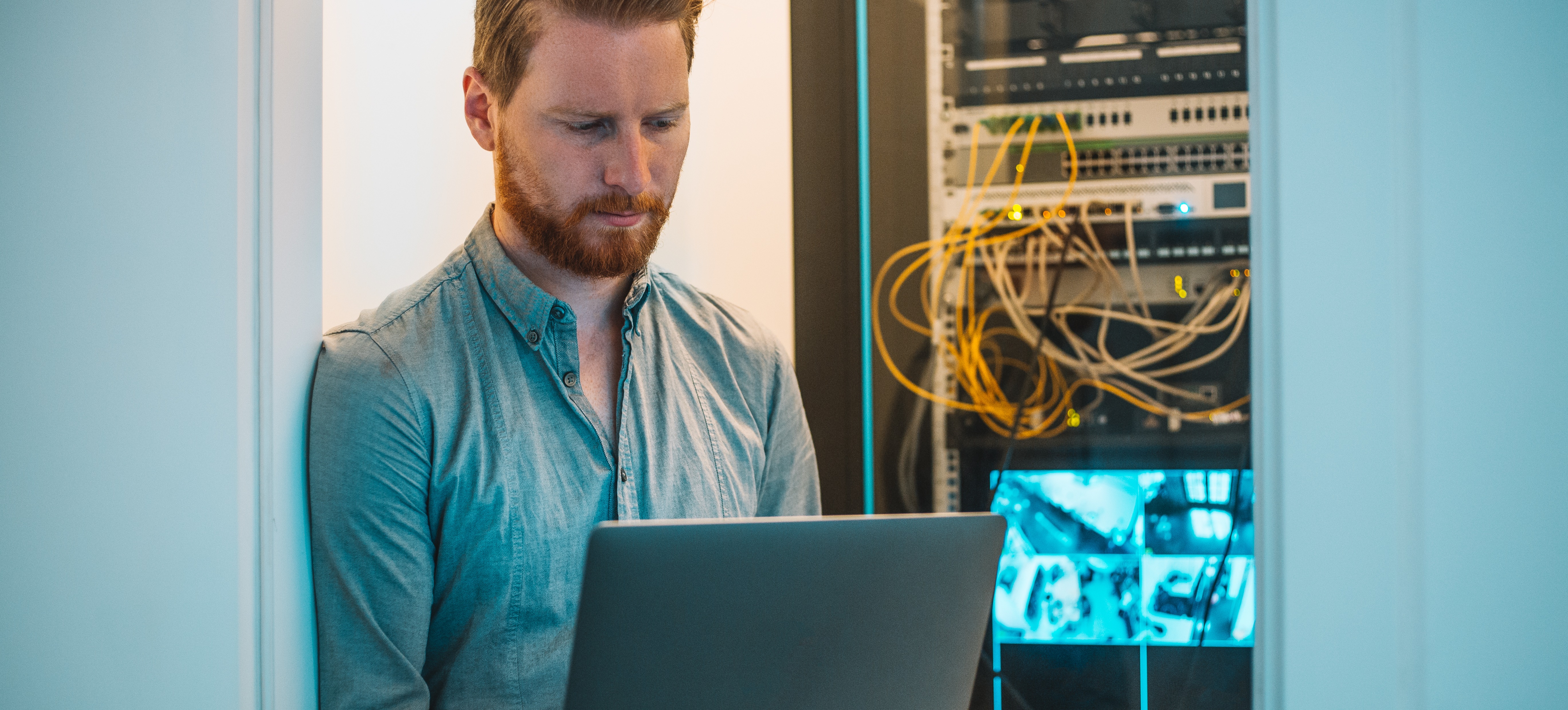[Featured Image] A cybersecurity technician is working on their laptop in the server room to protect files.

