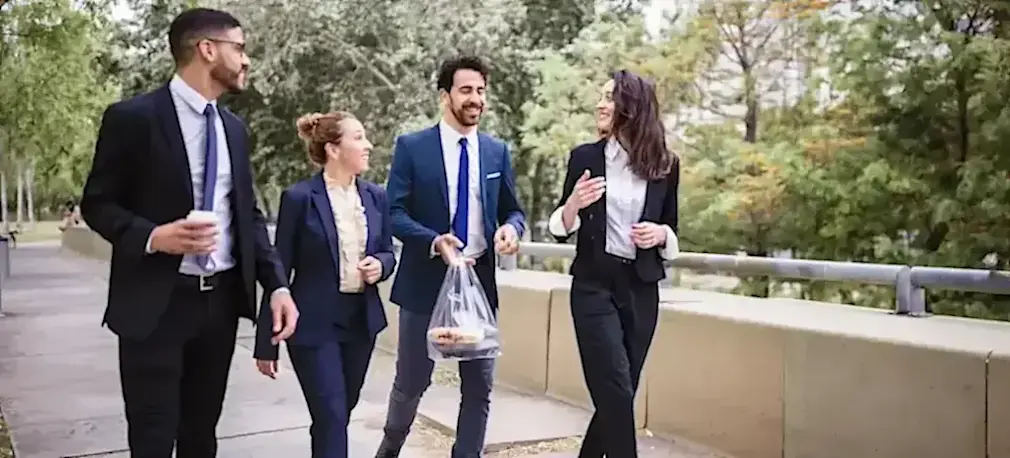 [Featured Image] A group of employees walks through a park to grab lunch on their breaks from their cybersecurity jobs in Houston. 
